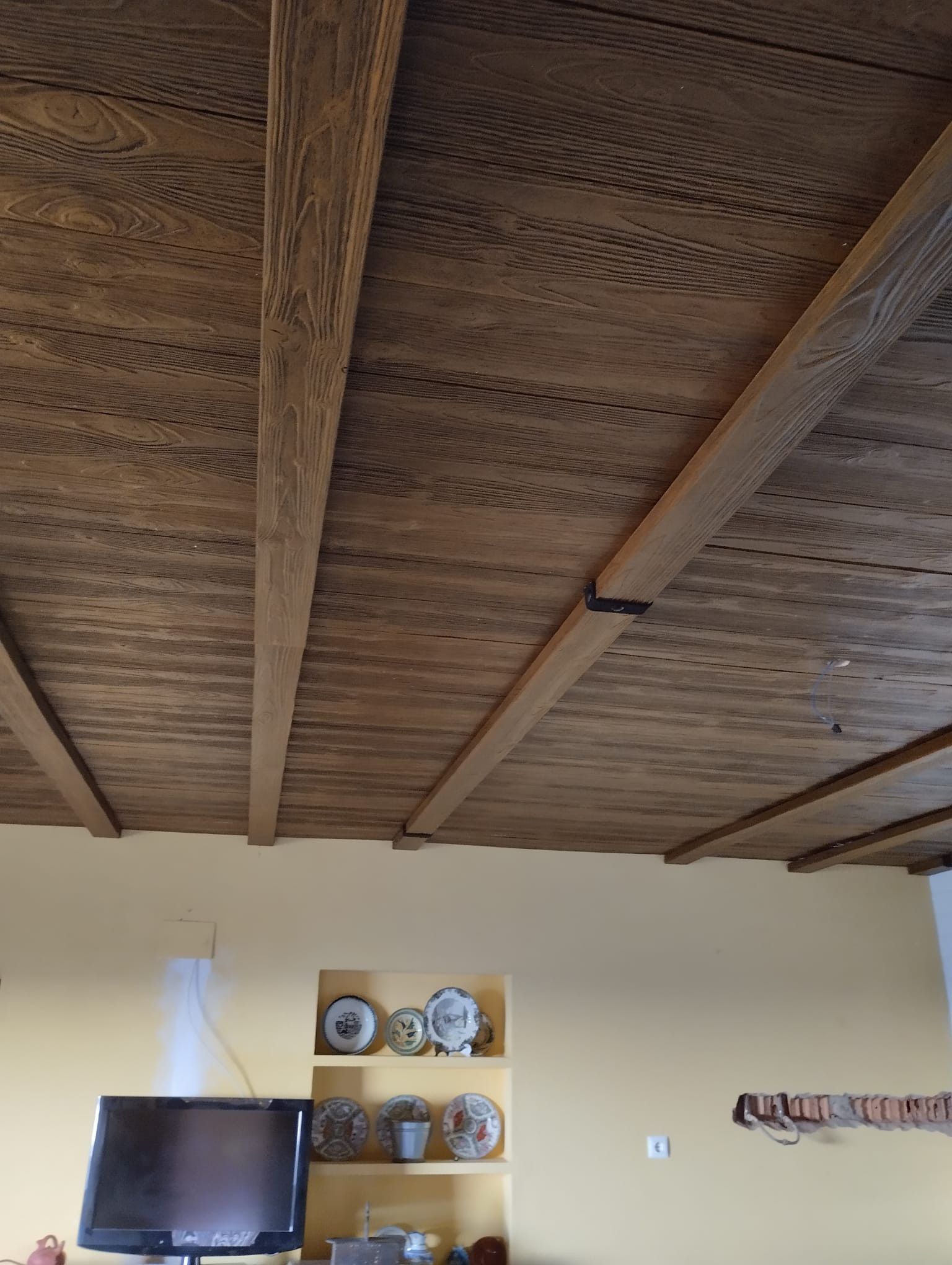 Una sala de estar con techo de madera y TV de pantalla plana.