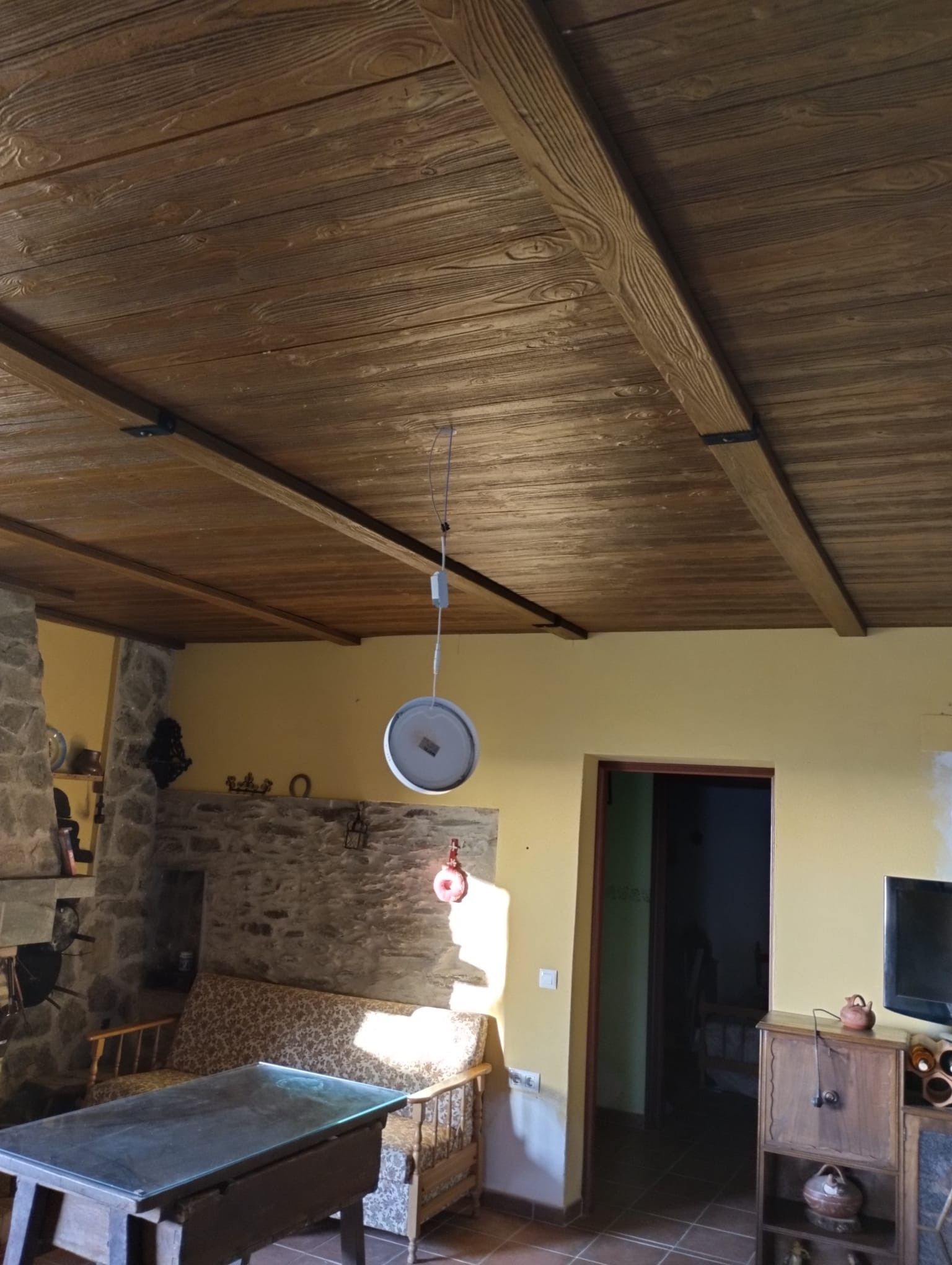 Una sala de estar con techo de madera y una mesa.
