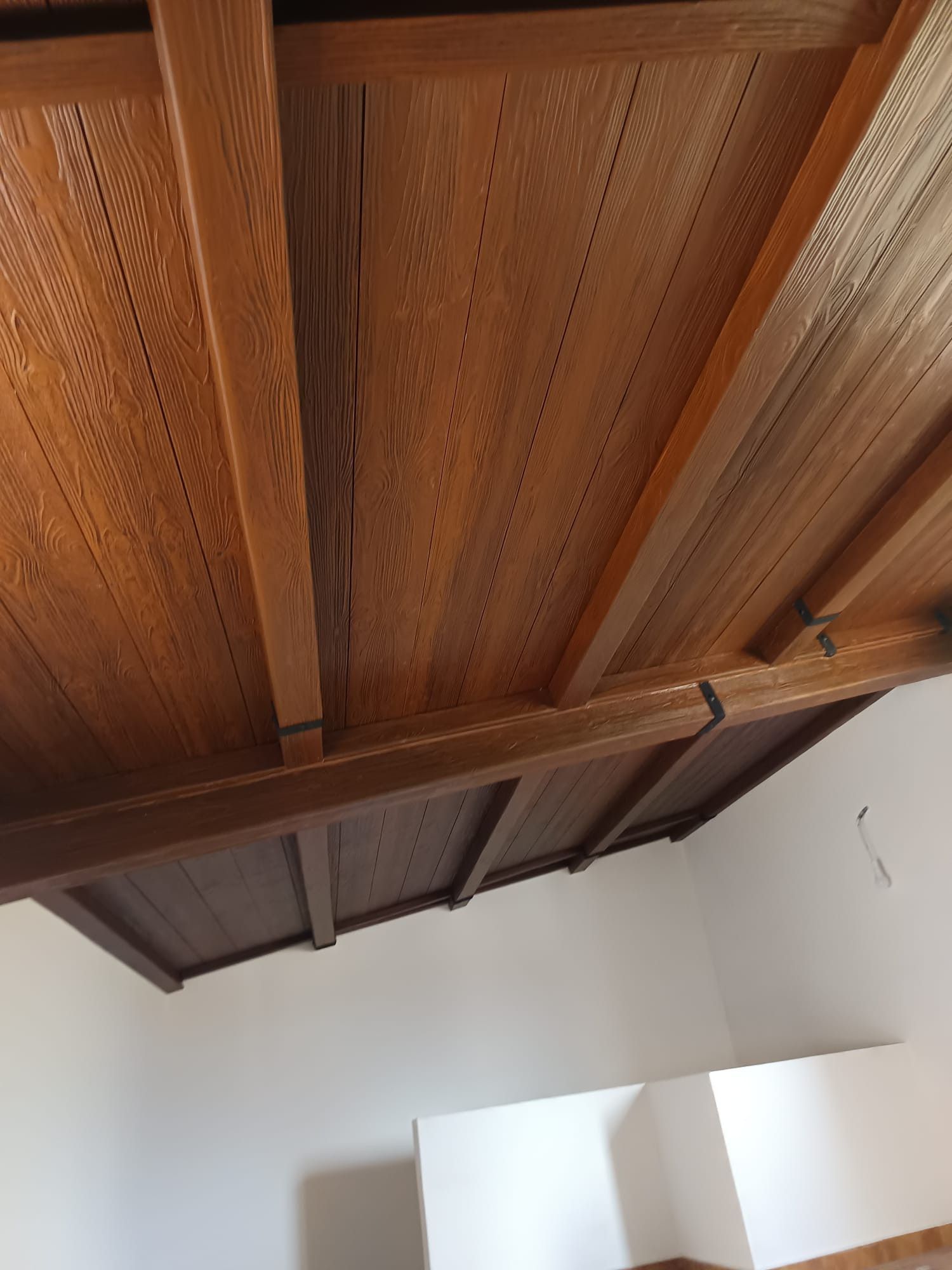 Una habitación con techo de madera y paredes blancas.