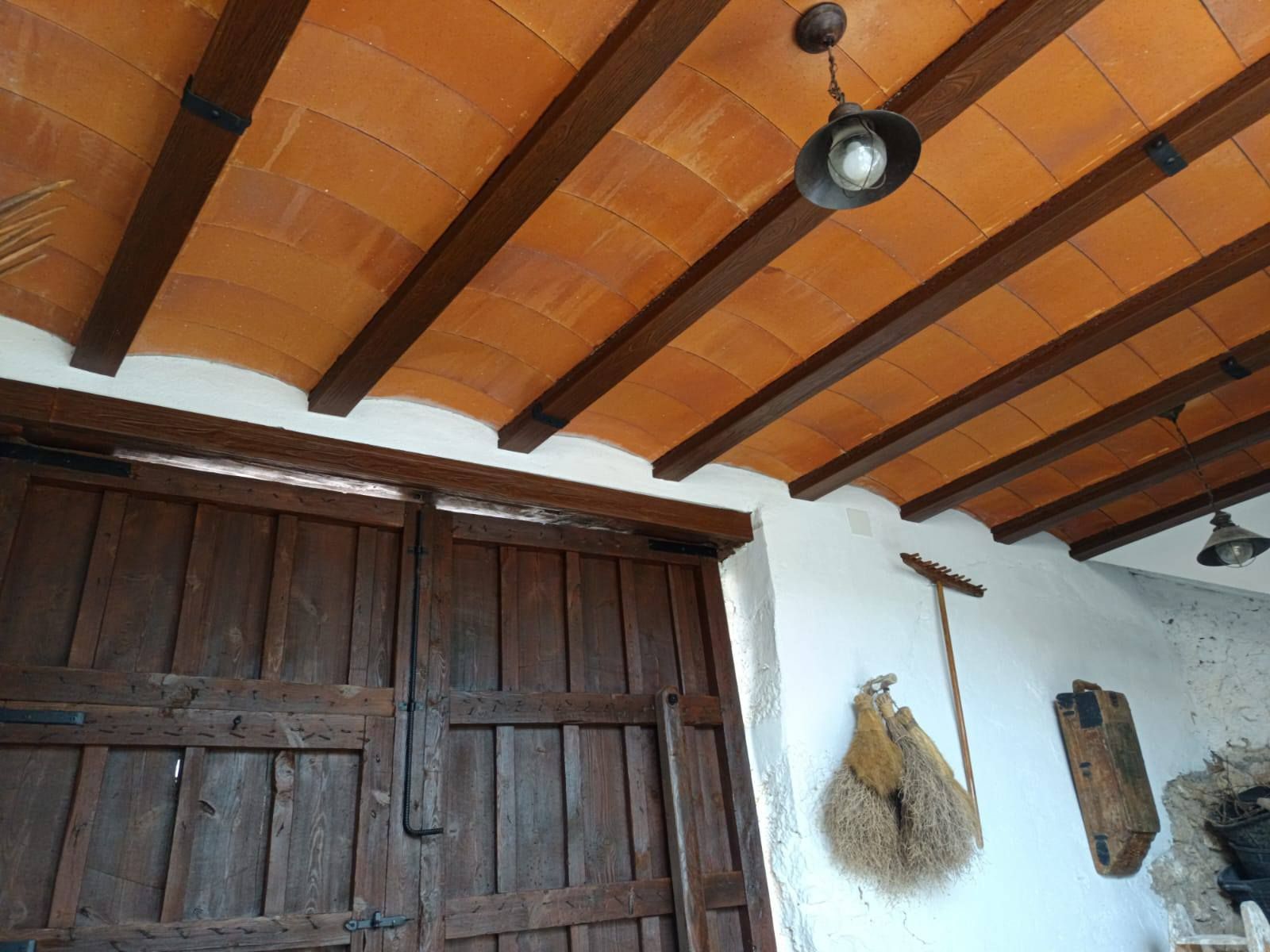 Un techo con vigas de madera y una lámpara colgando de él.