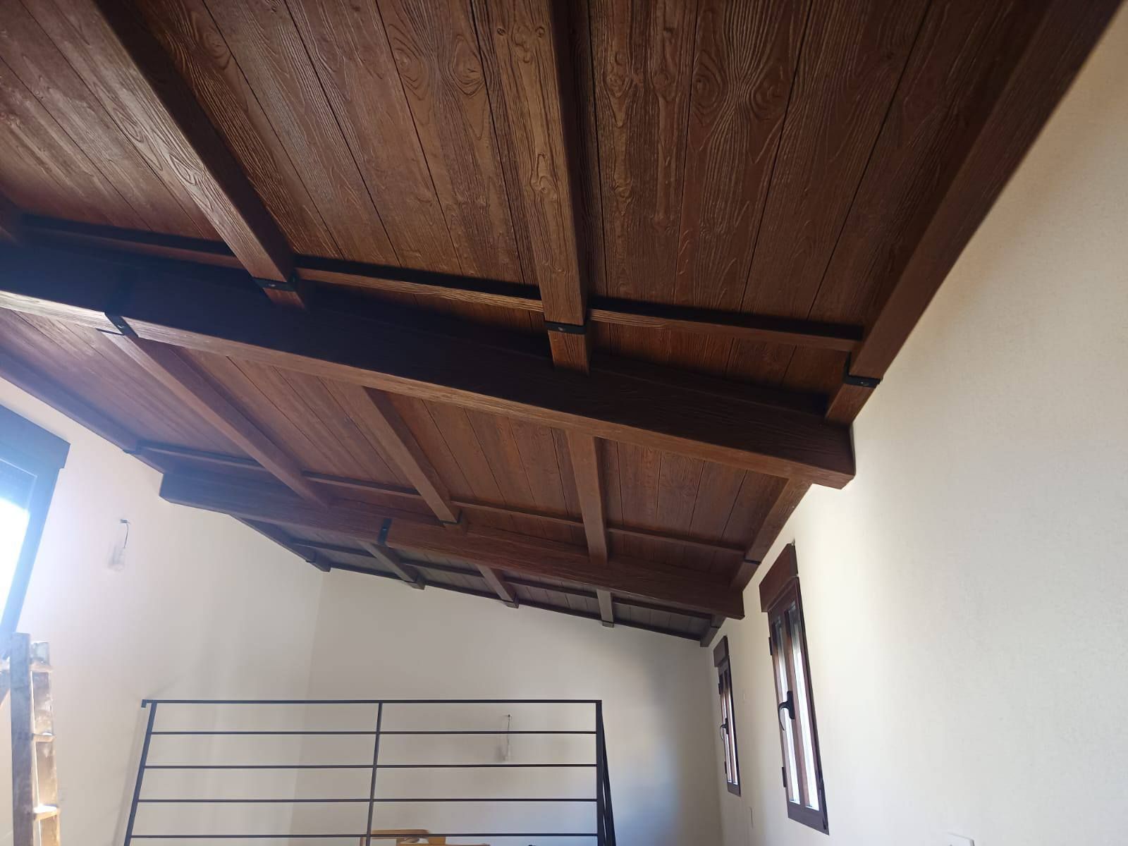 Una habitación con techo de madera y paredes blancas.