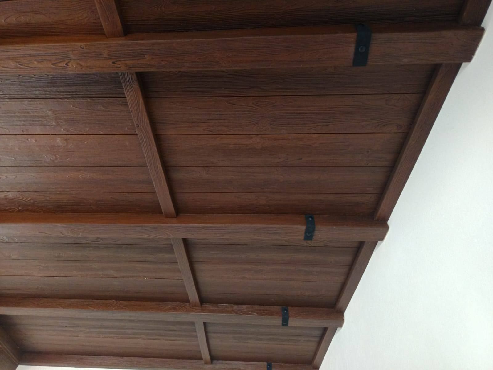 Un techo de madera con una pared blanca al fondo.