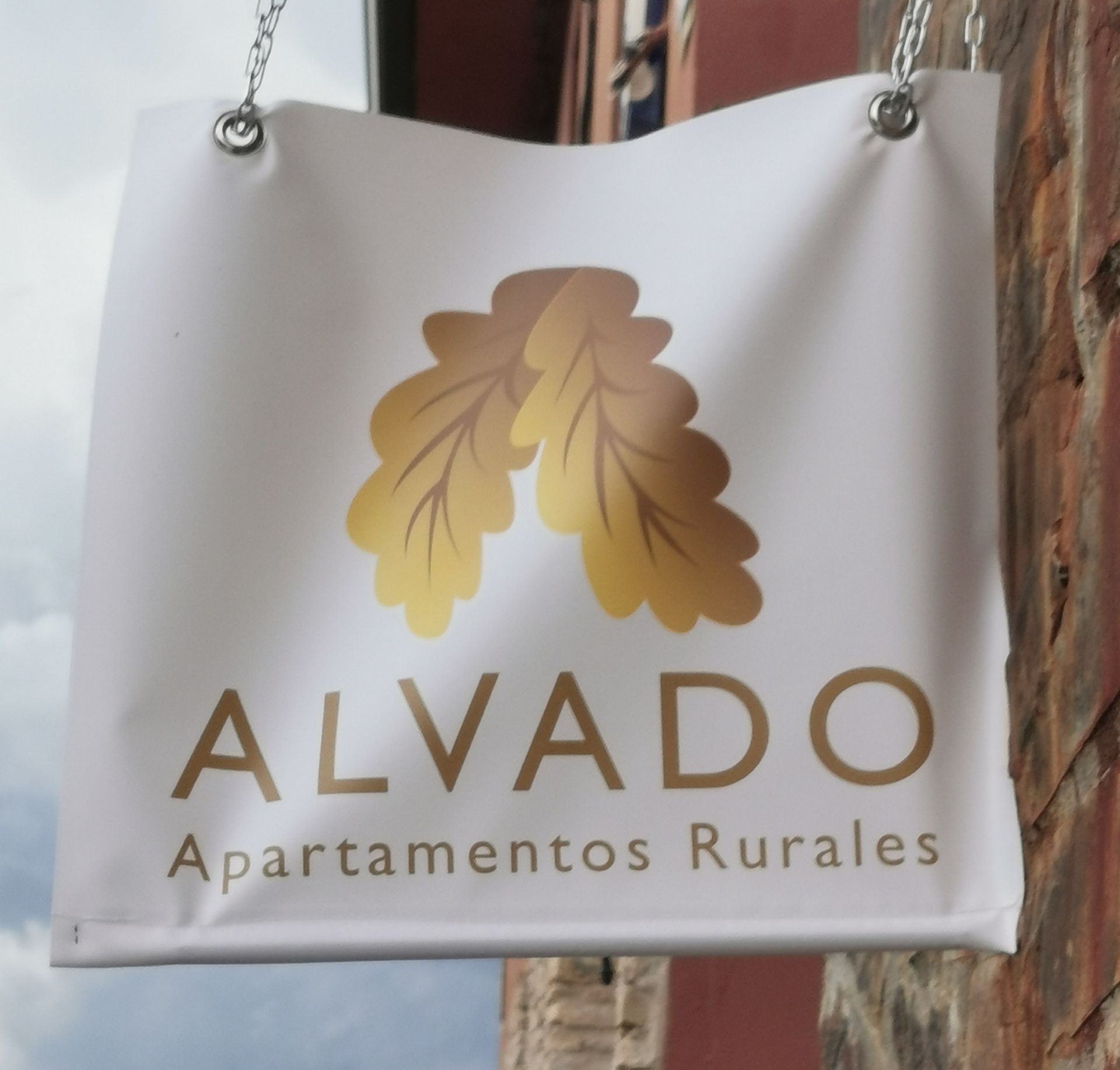 Cartel de "ALVADO Apartamentos Rurales" con logo en hoja de roble dorado.