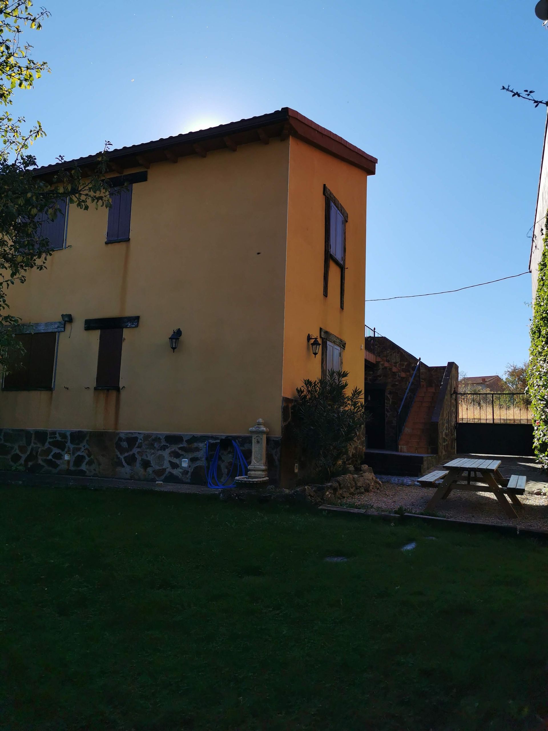 Una casa colorida con ribetes verdes en una colina con cielo azul. Un sendero conduce a la casa.