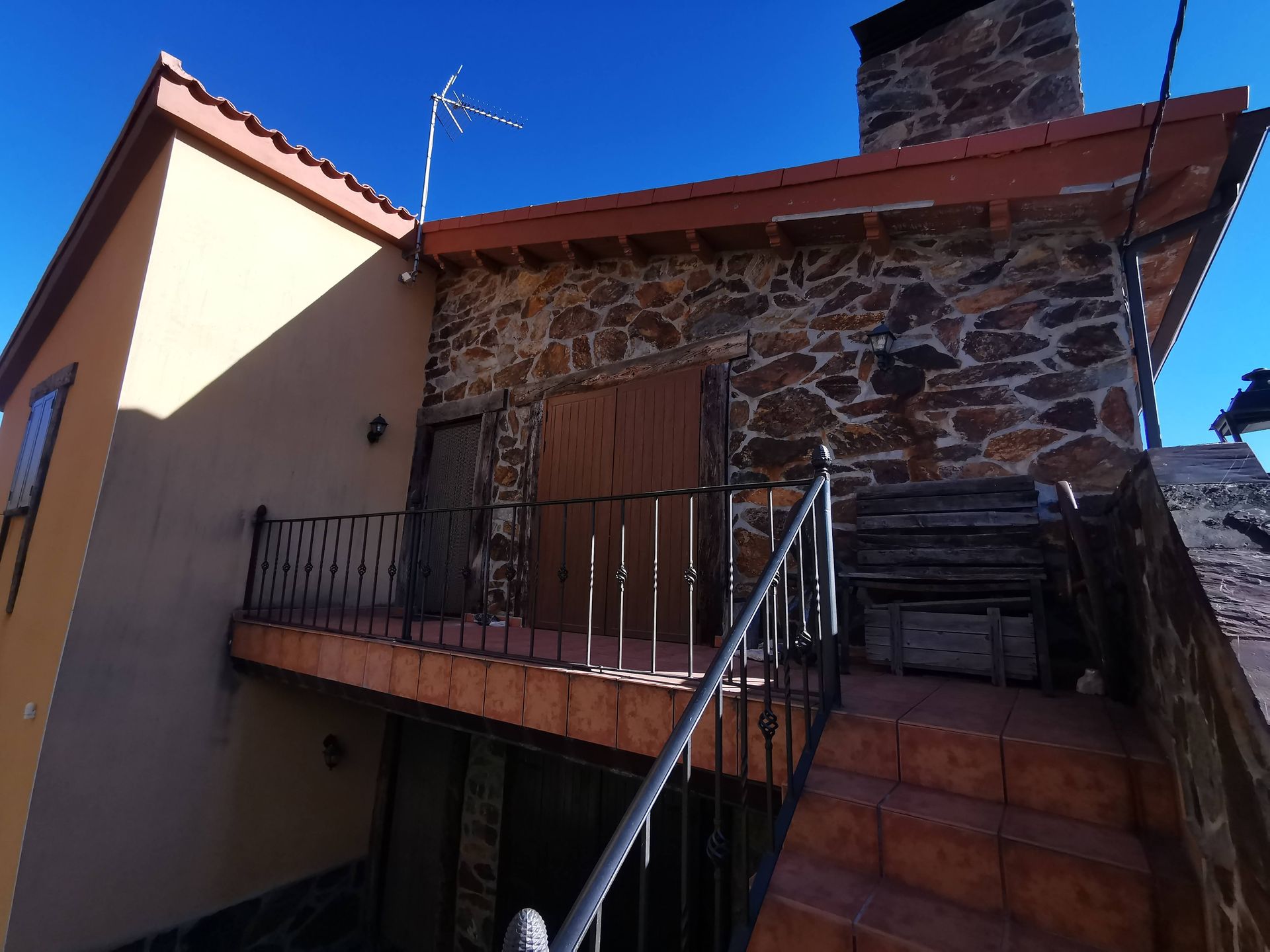 Casa amarilla con molduras blancas, porche y jardín. Árboles verdes al fondo.