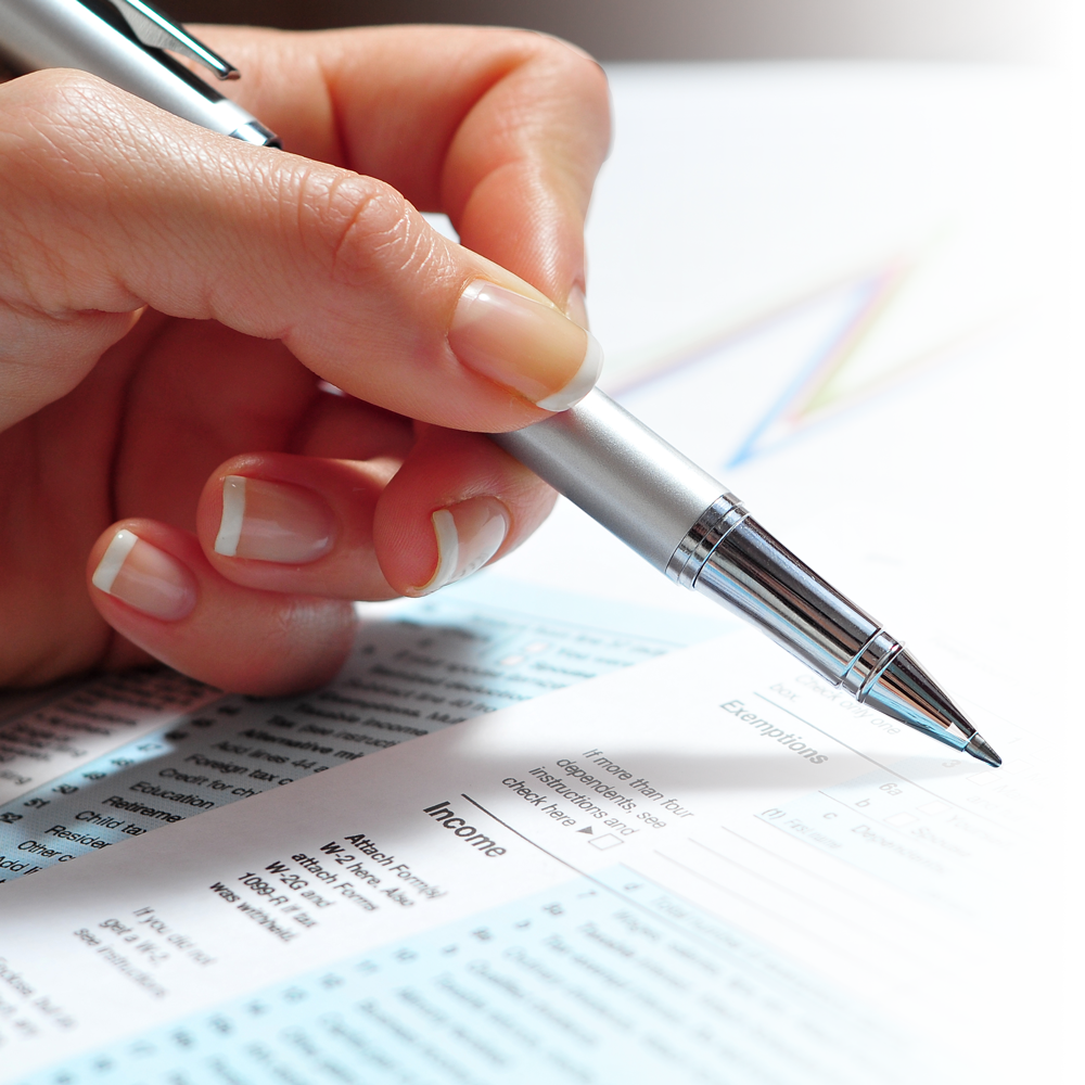 Main tenant un stylo argenté, écrivant sur un formulaire comportant des sections bleues et blanches.