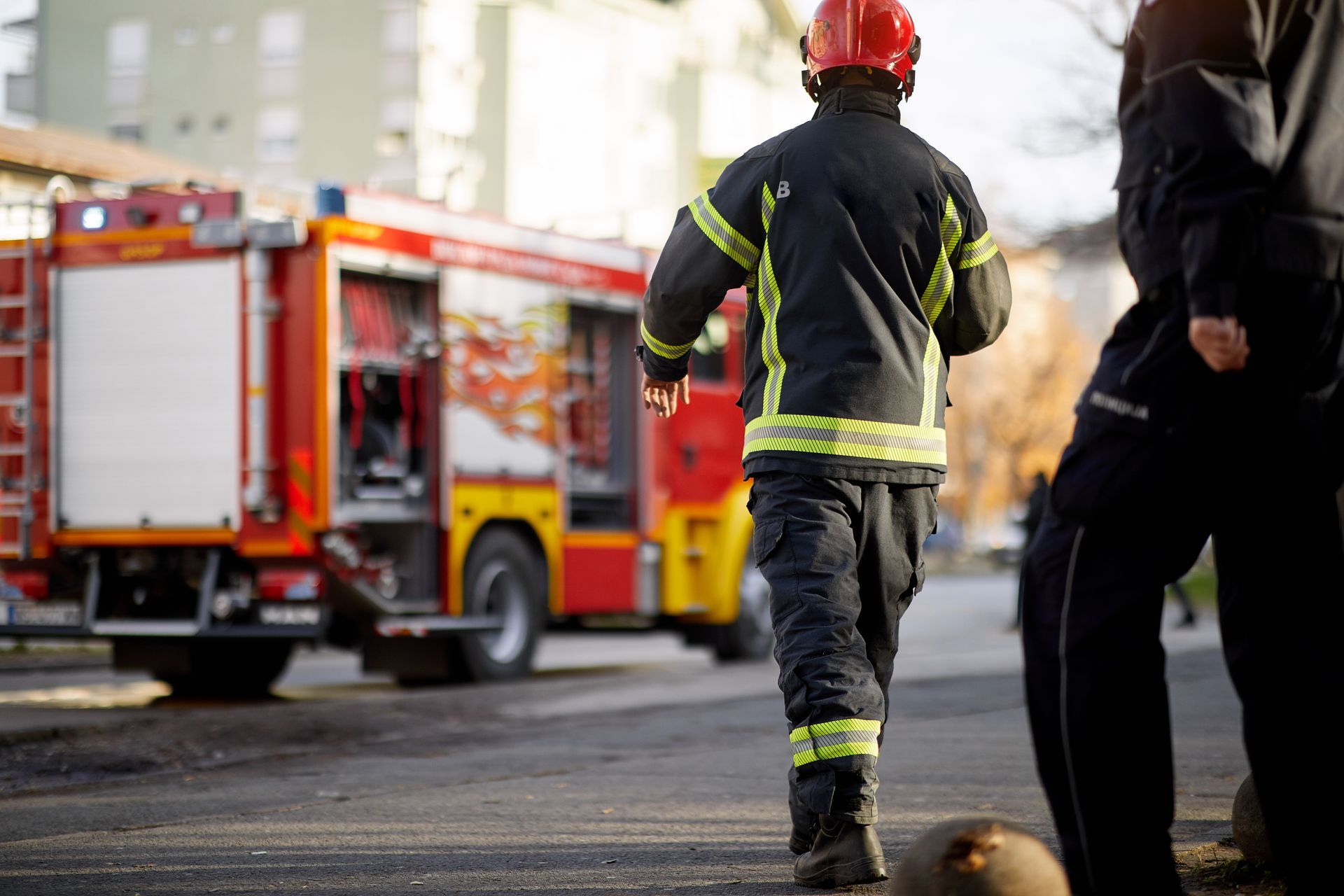 Des pompiers en tenue réfléchissante près d'un camion de pompiers rouge dans une rue de la ville