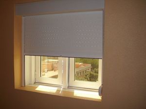 Una ventana con una persiana blanca y una vista de un edificio.