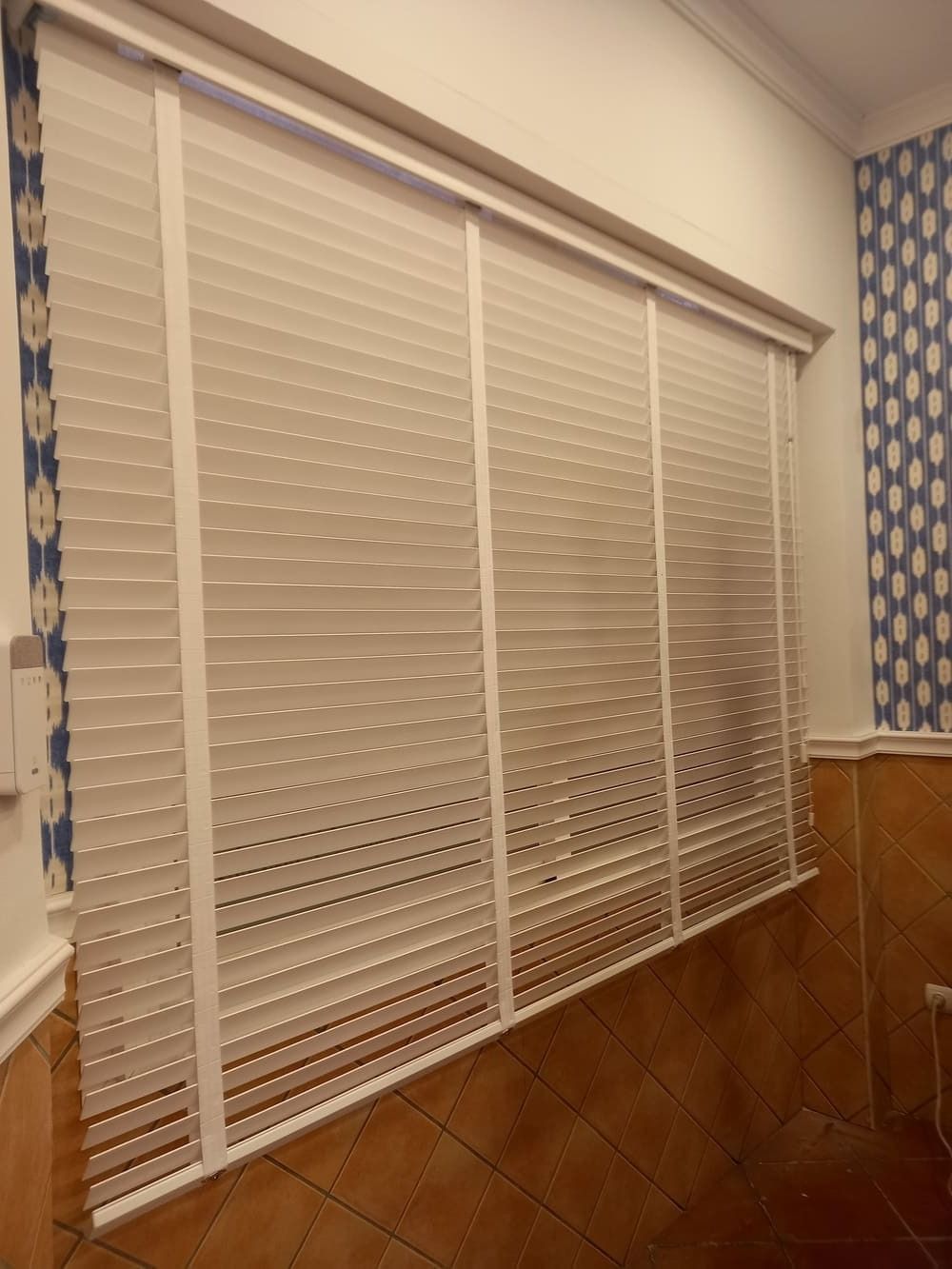 Una ventana con persianas blancas en una habitación.