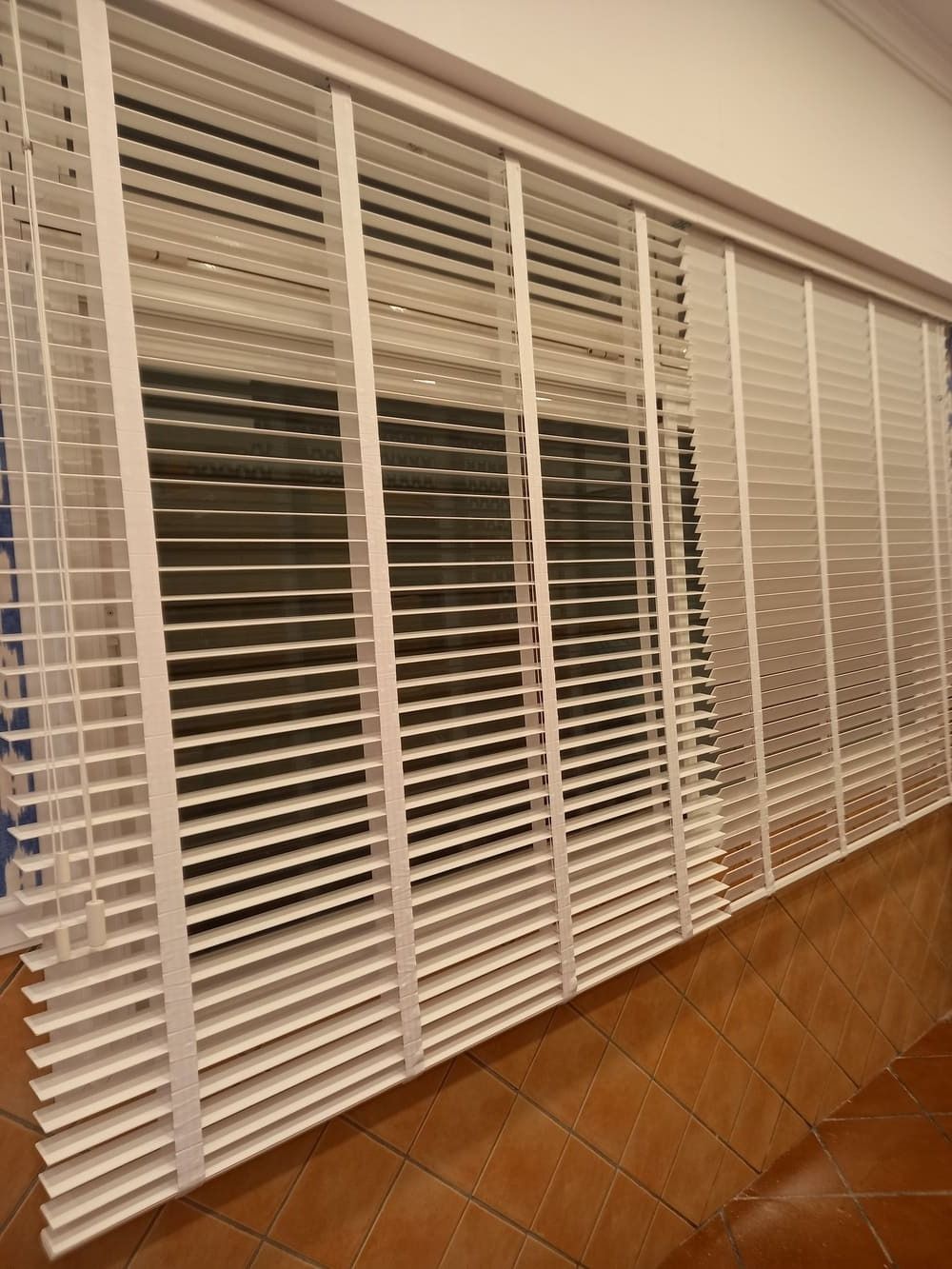 Una hilera de persianas blancas en una ventana de una habitación.
