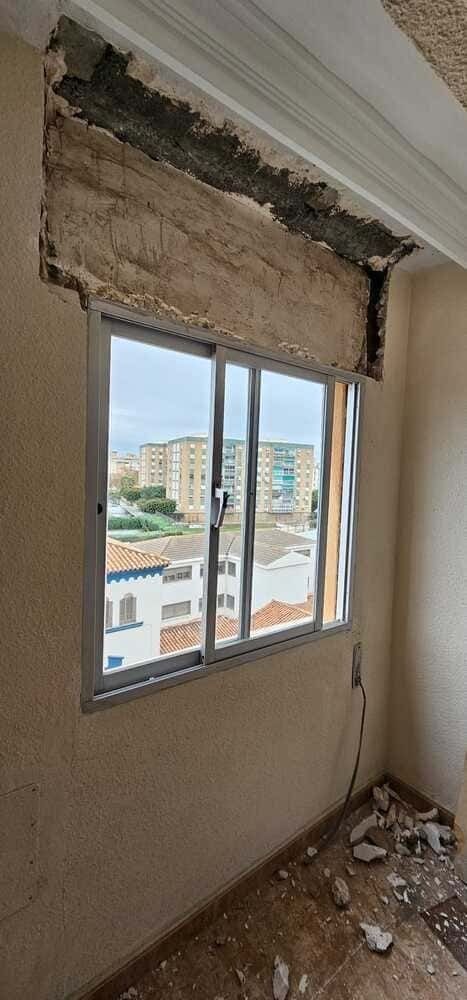 Una habitación con una ventana y un agujero en la pared.