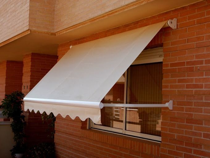 Un toldo blanco cuelga sobre una ventana de un edificio de ladrillo.