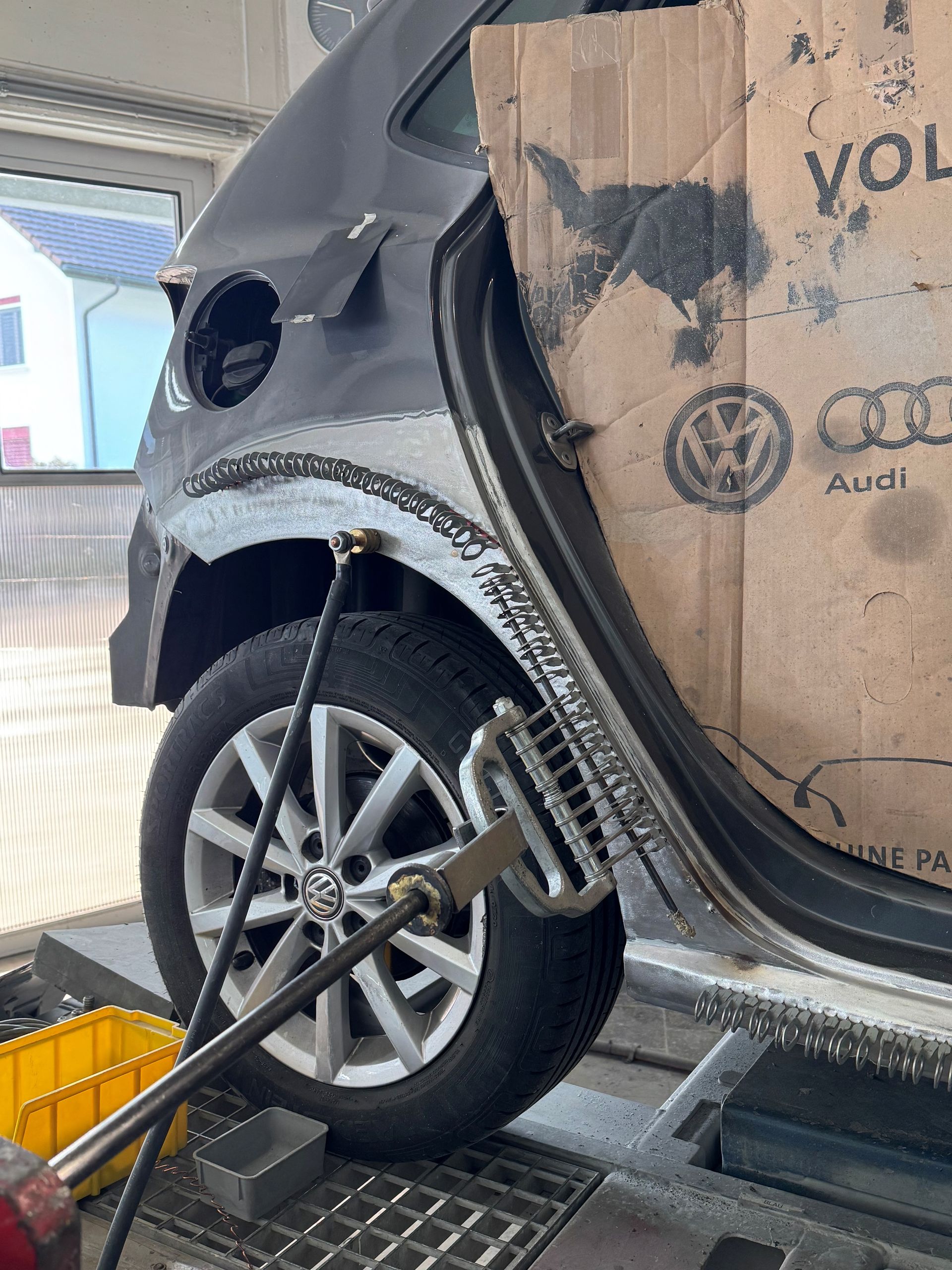 Ein Mann kniet vor einem Auto.