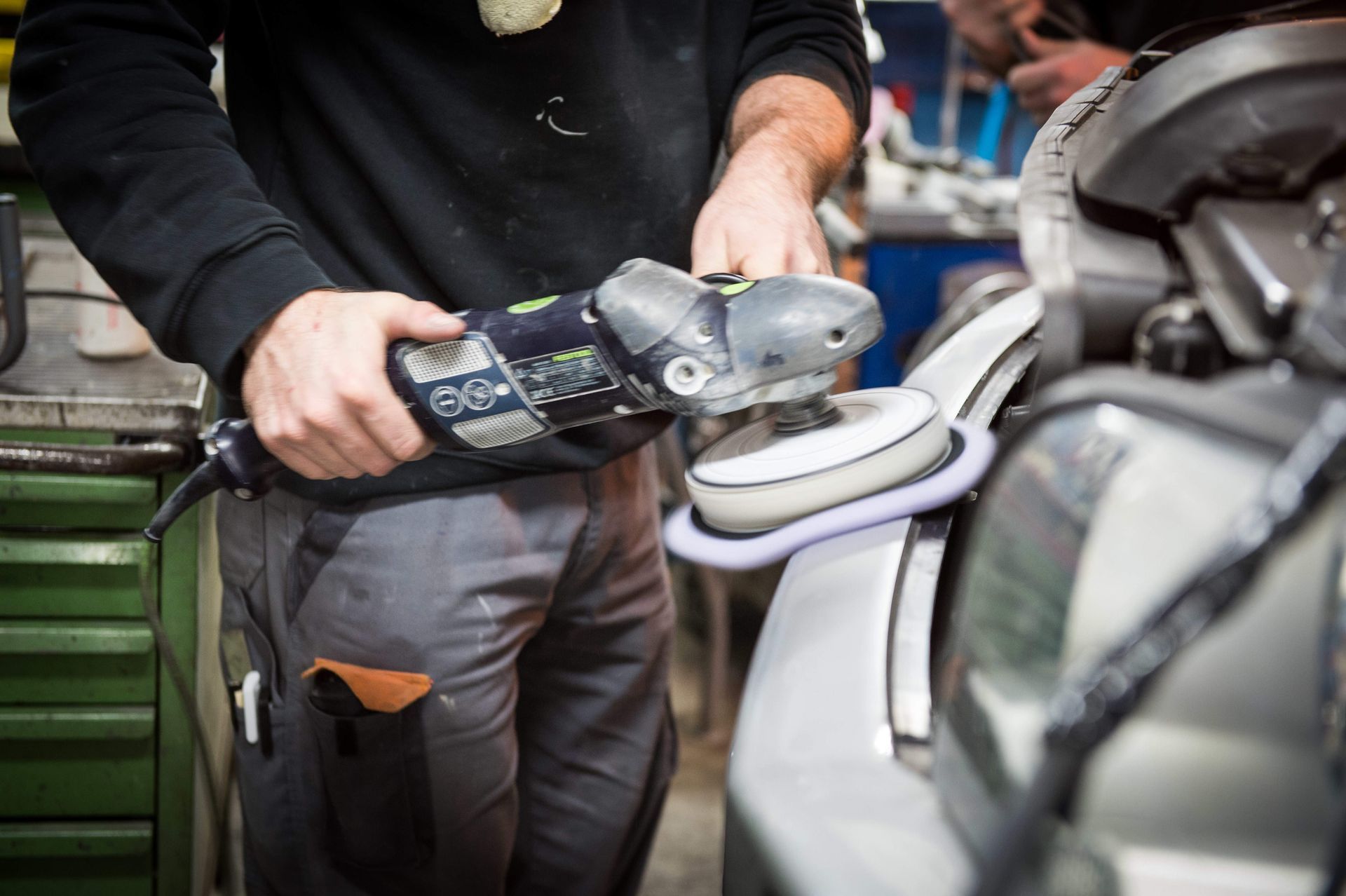 Ein Mann poliert ein Auto mit einer Maschine.
