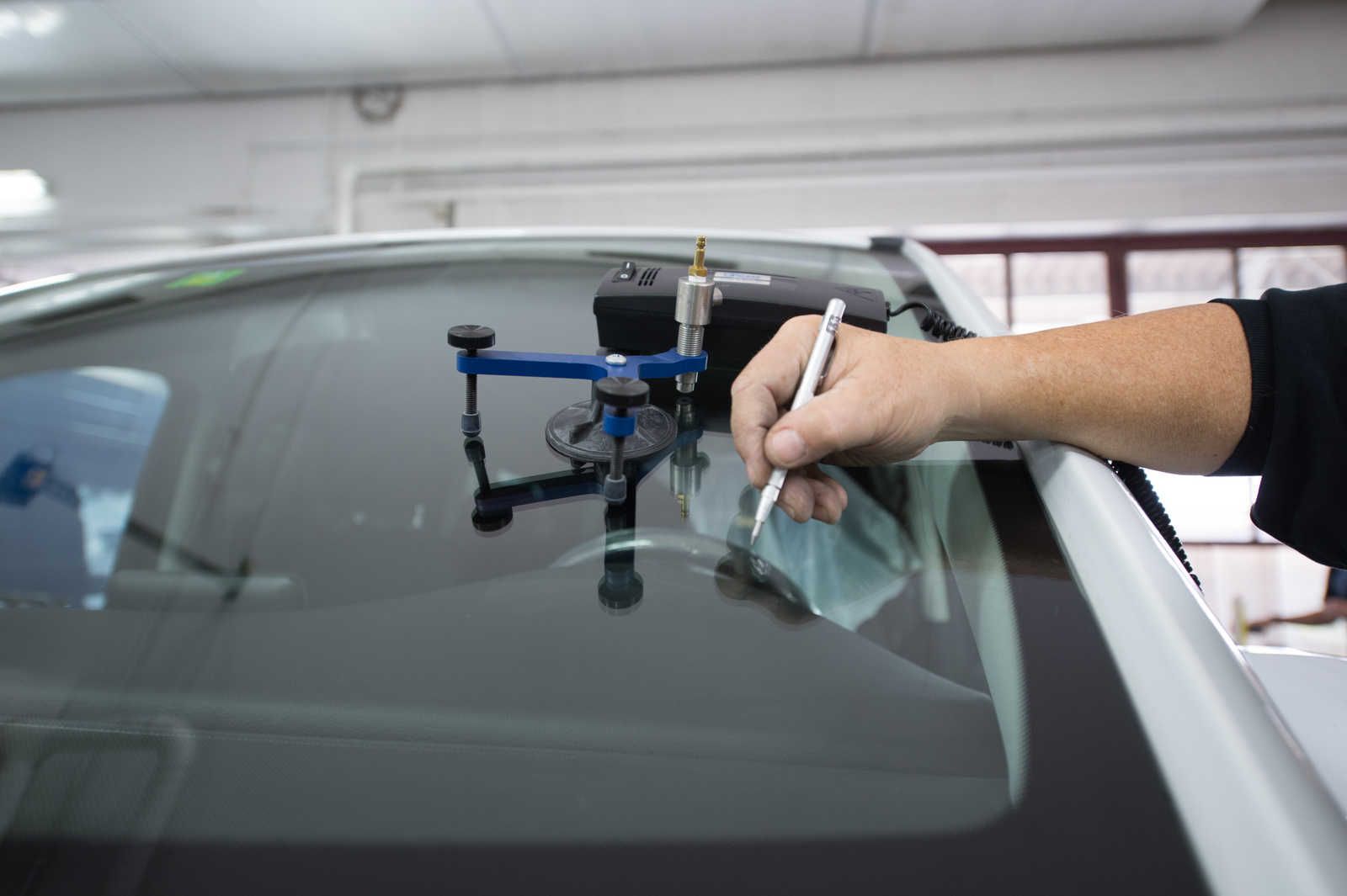 Eine Person schreibt mit einem Stift auf eine Windschutzscheibe eines Autos.