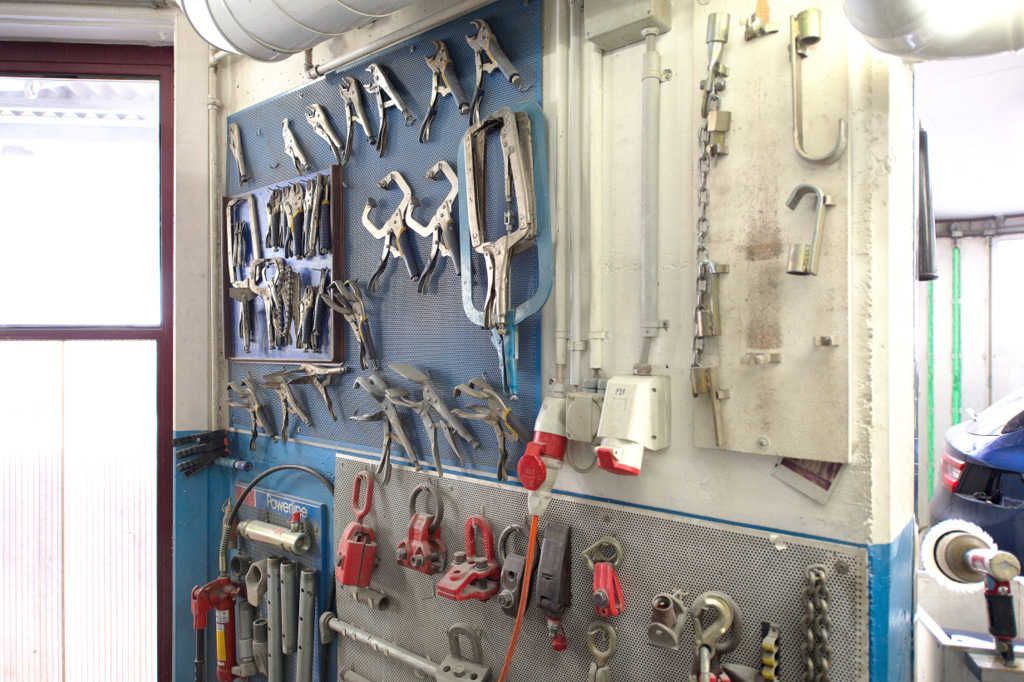 In einer Garage hängt ein Haufen Werkzeuge an der Wand.