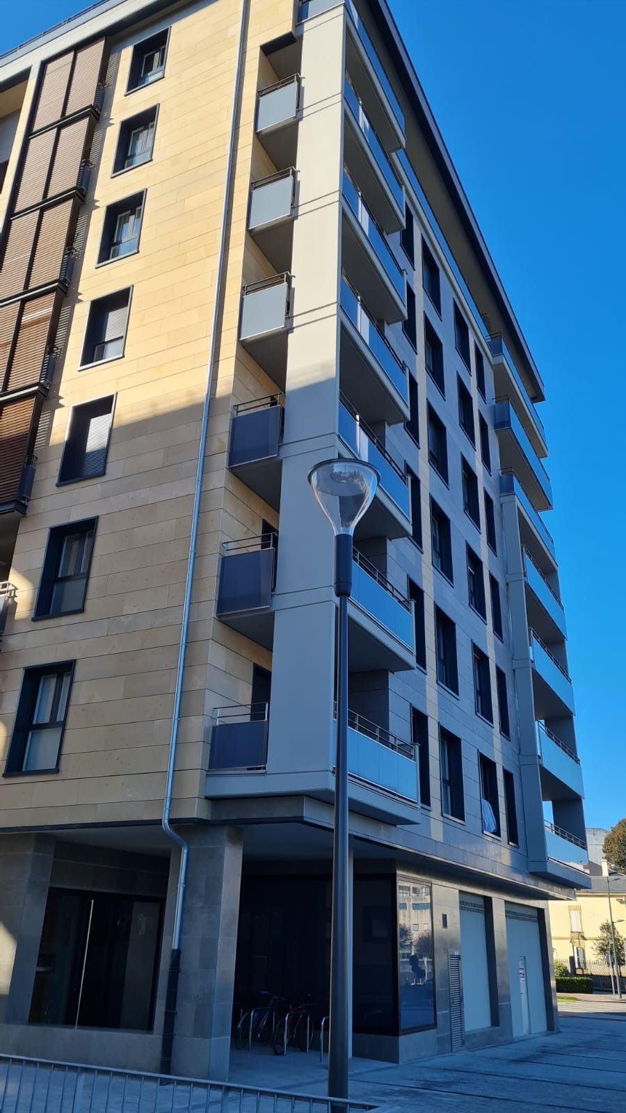 Un edificio alto con balcones y una farola delante de él.