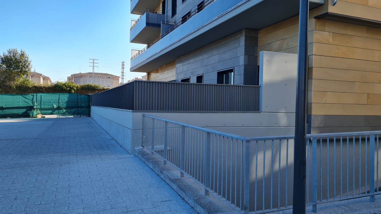 Un edificio con una valla a su alrededor y un estacionamiento delante de él.