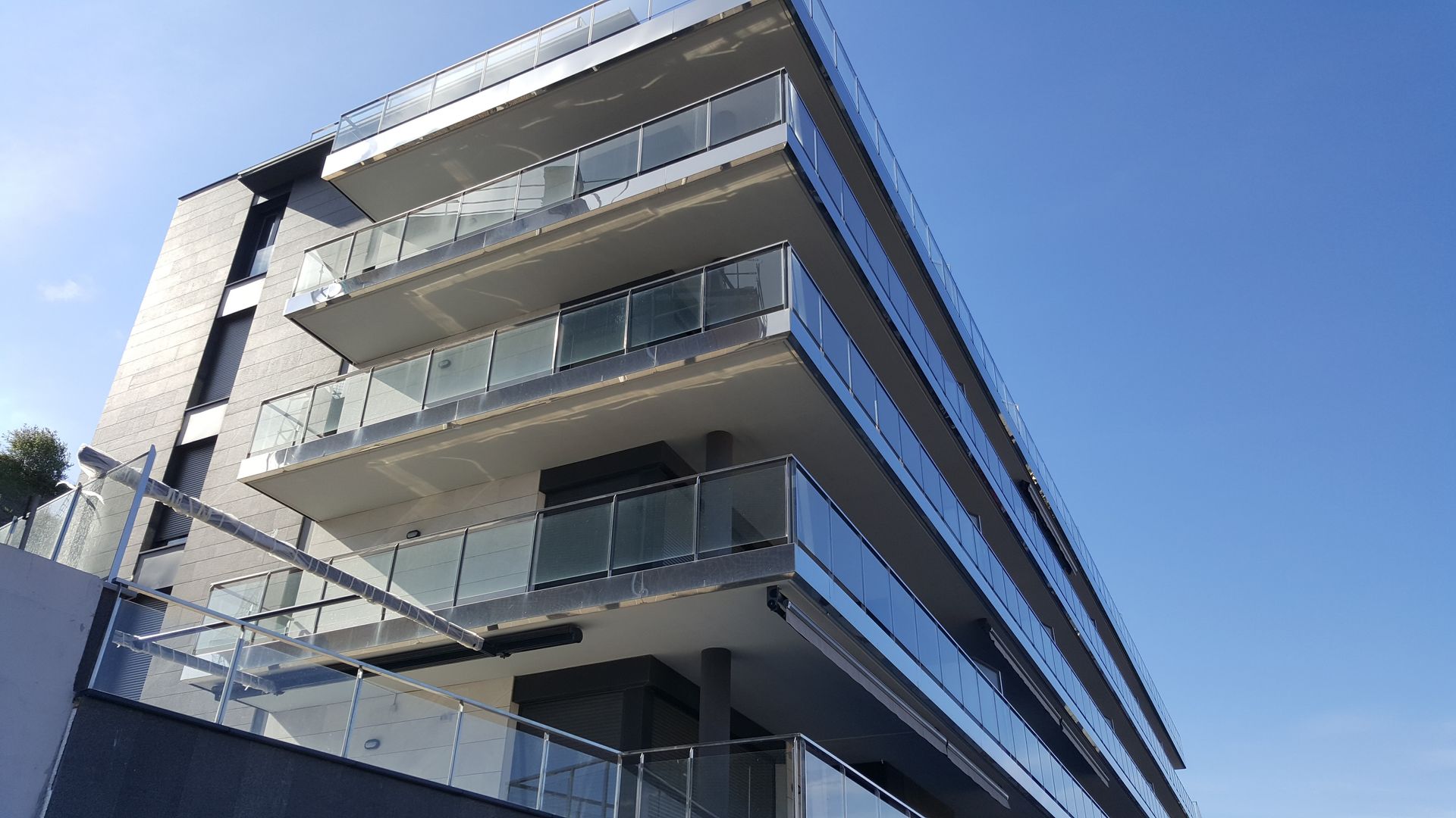 Un gran edificio con muchos balcones y un cielo azul al fondo.