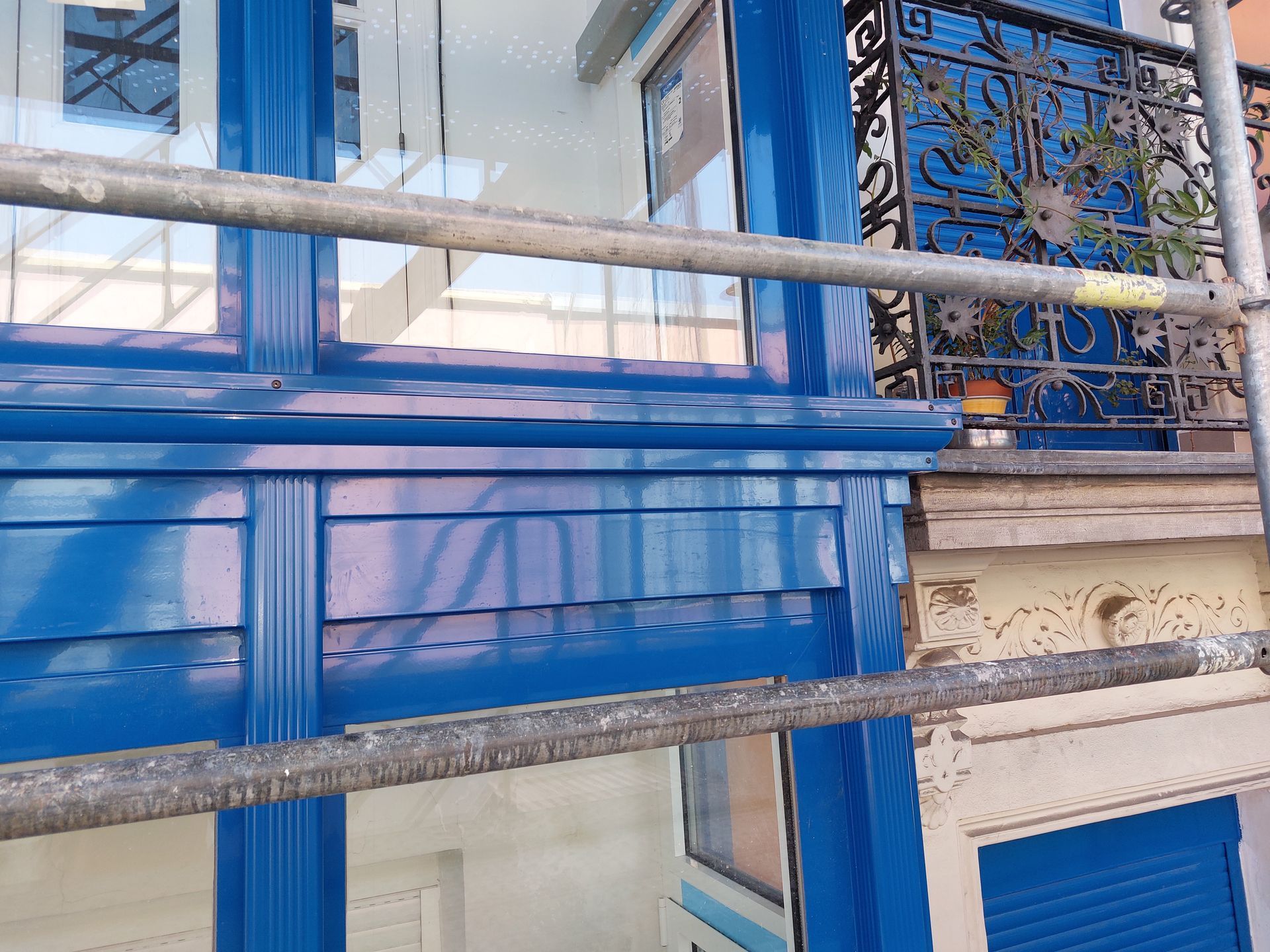 Un edificio azul con un balcón y andamios alrededor.