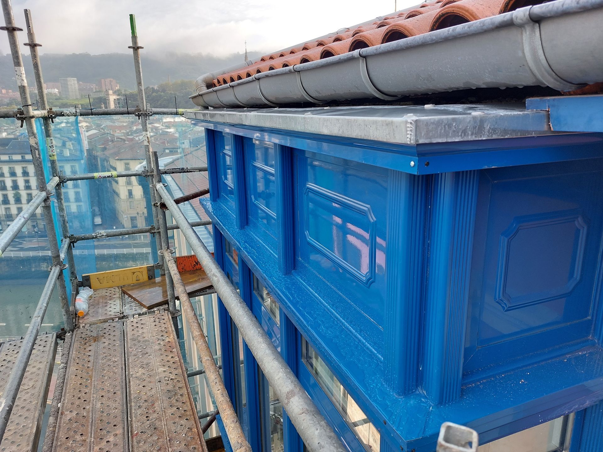 Un edificio azul con andamios alrededor está en construcción.