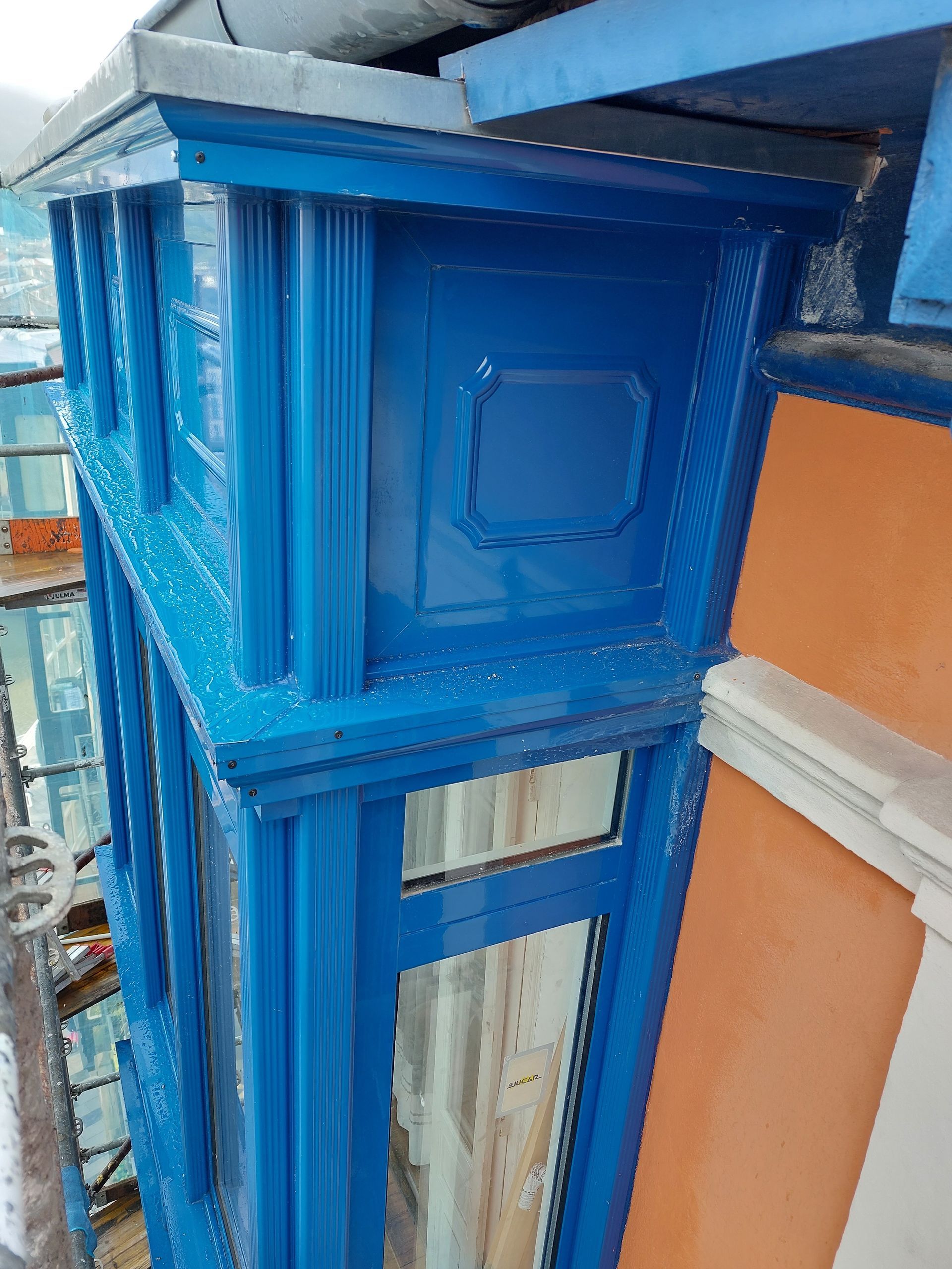 Una ventana azul en el costado de un edificio.