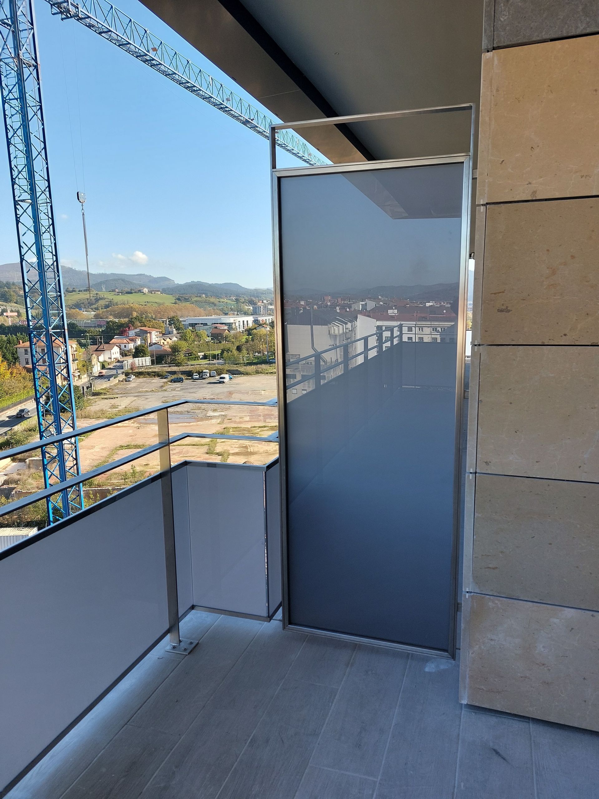 Un balcón con una pantalla gris y una vista de una ciudad.