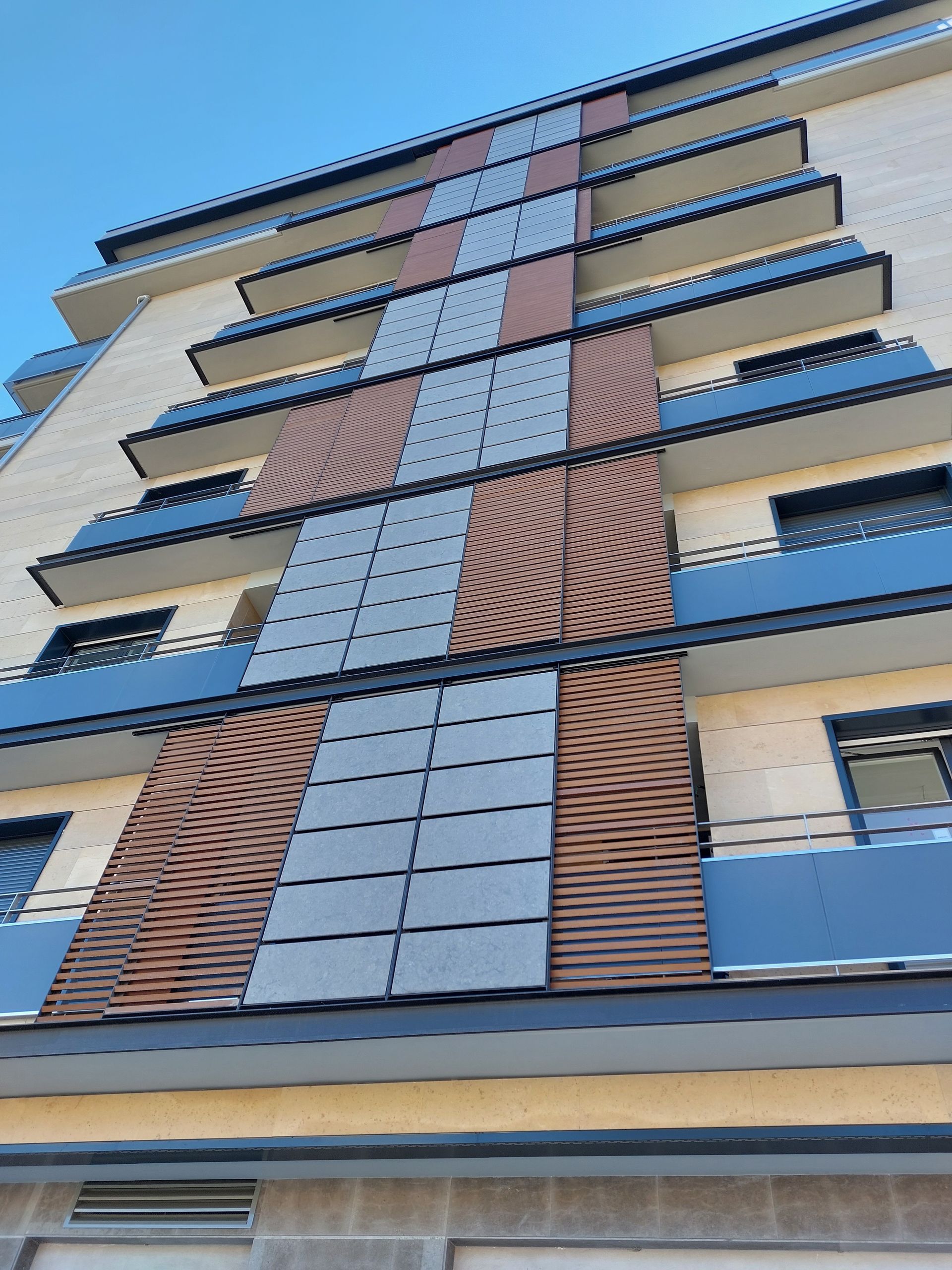 Un edificio alto con balcones y un cielo azul al fondo.