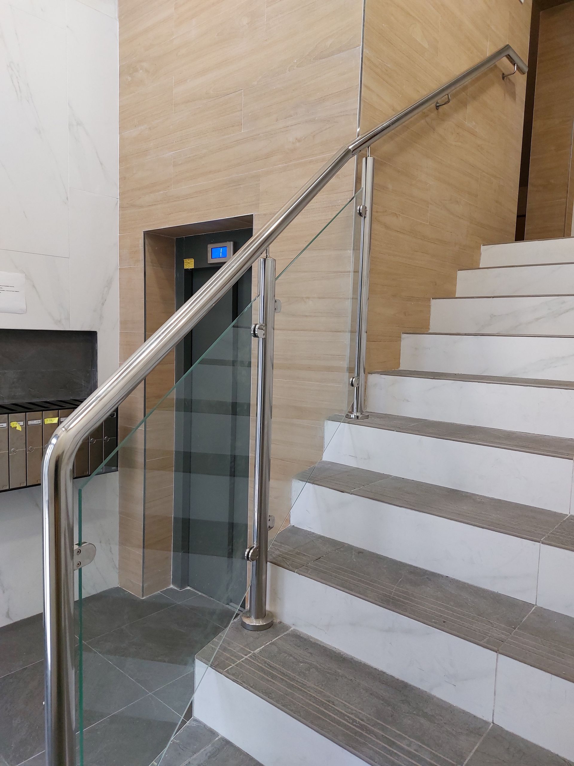 Un conjunto de escaleras con barandilla de acero inoxidable y barandilla de cristal.