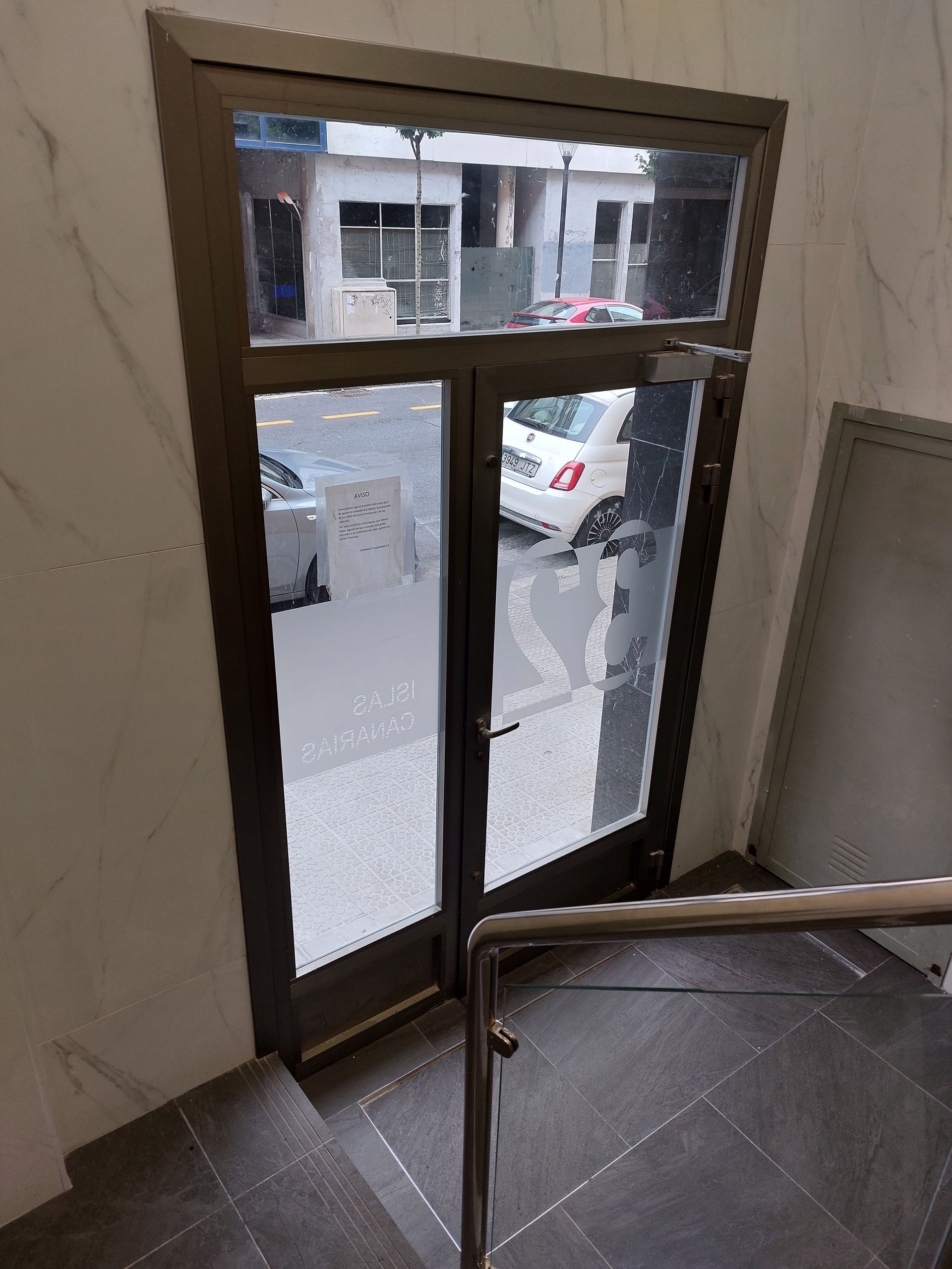 Una escalera que conduce a una puerta con un coche aparcado delante de ella.