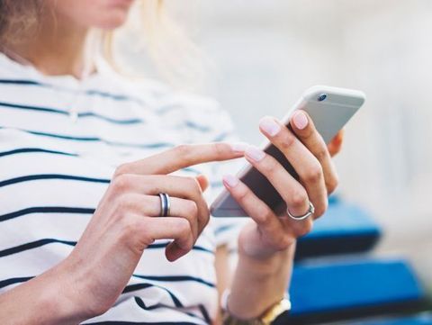 Una mujer está usando un teléfono celular con un anillo en su dedo.