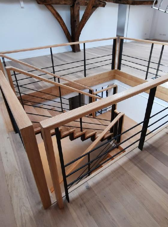 Una escalera de madera con barandilla negra en una habitación.