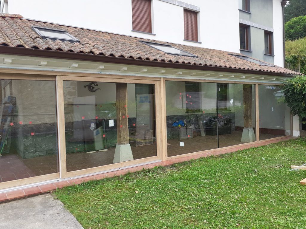 Una casa con muchas ventanas y un césped delante de ella.