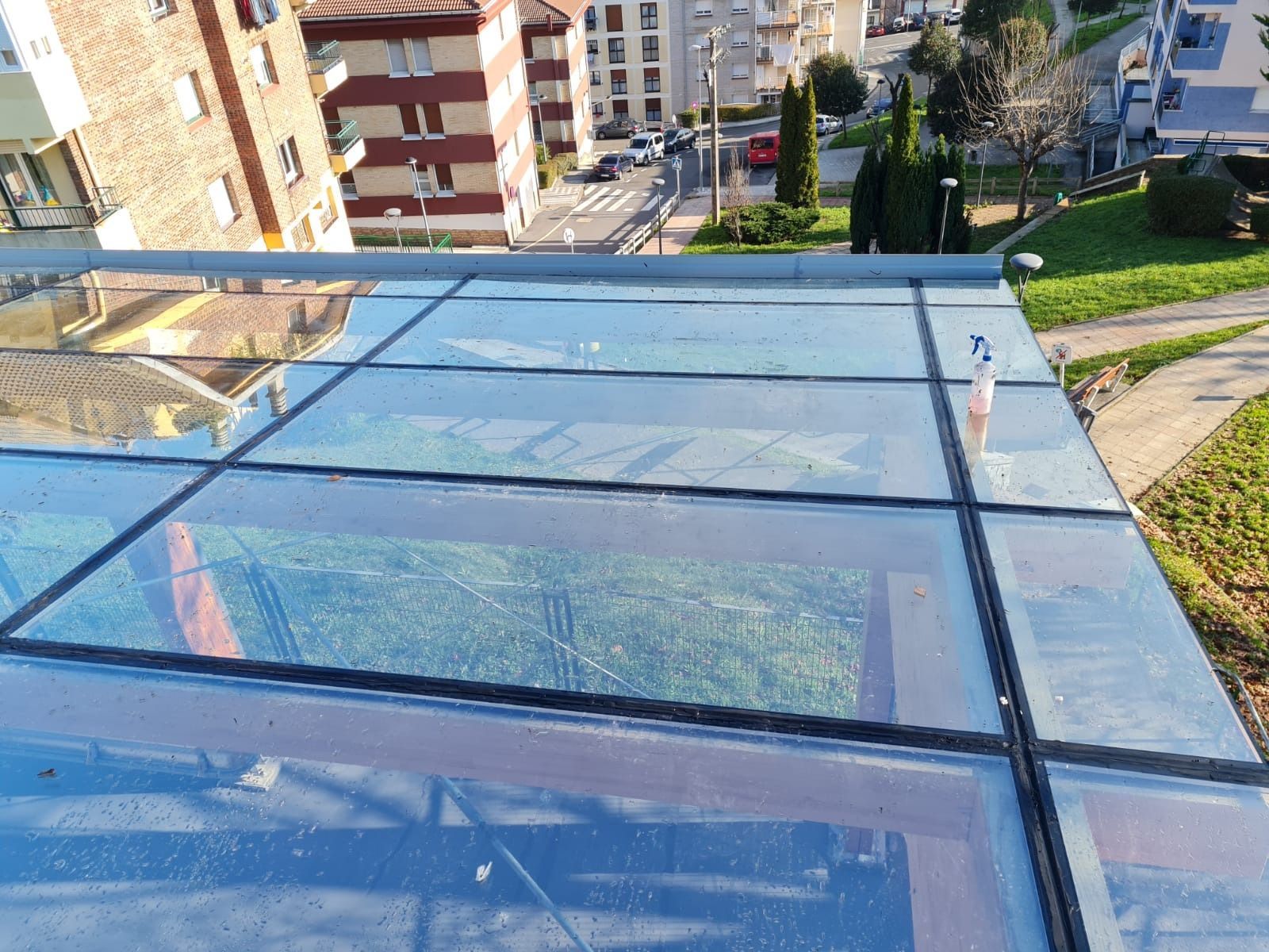 Un techo de cristal con vista a un parque y edificios al fondo.