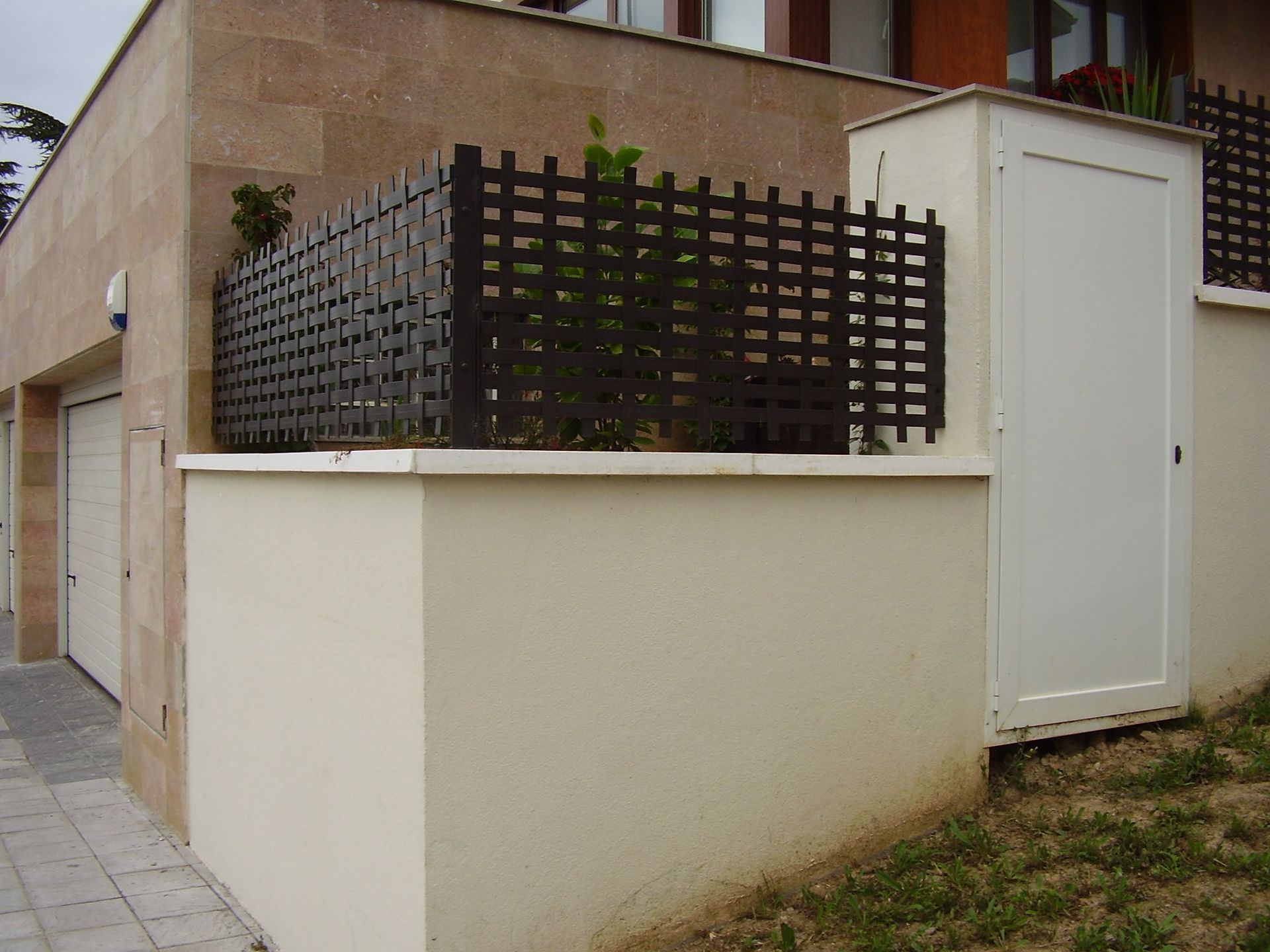 Una pared blanca con una valla negra y una puerta blanca.