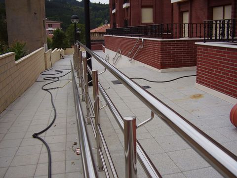 Una manguera está conectada a una barandilla de acero inoxidable.