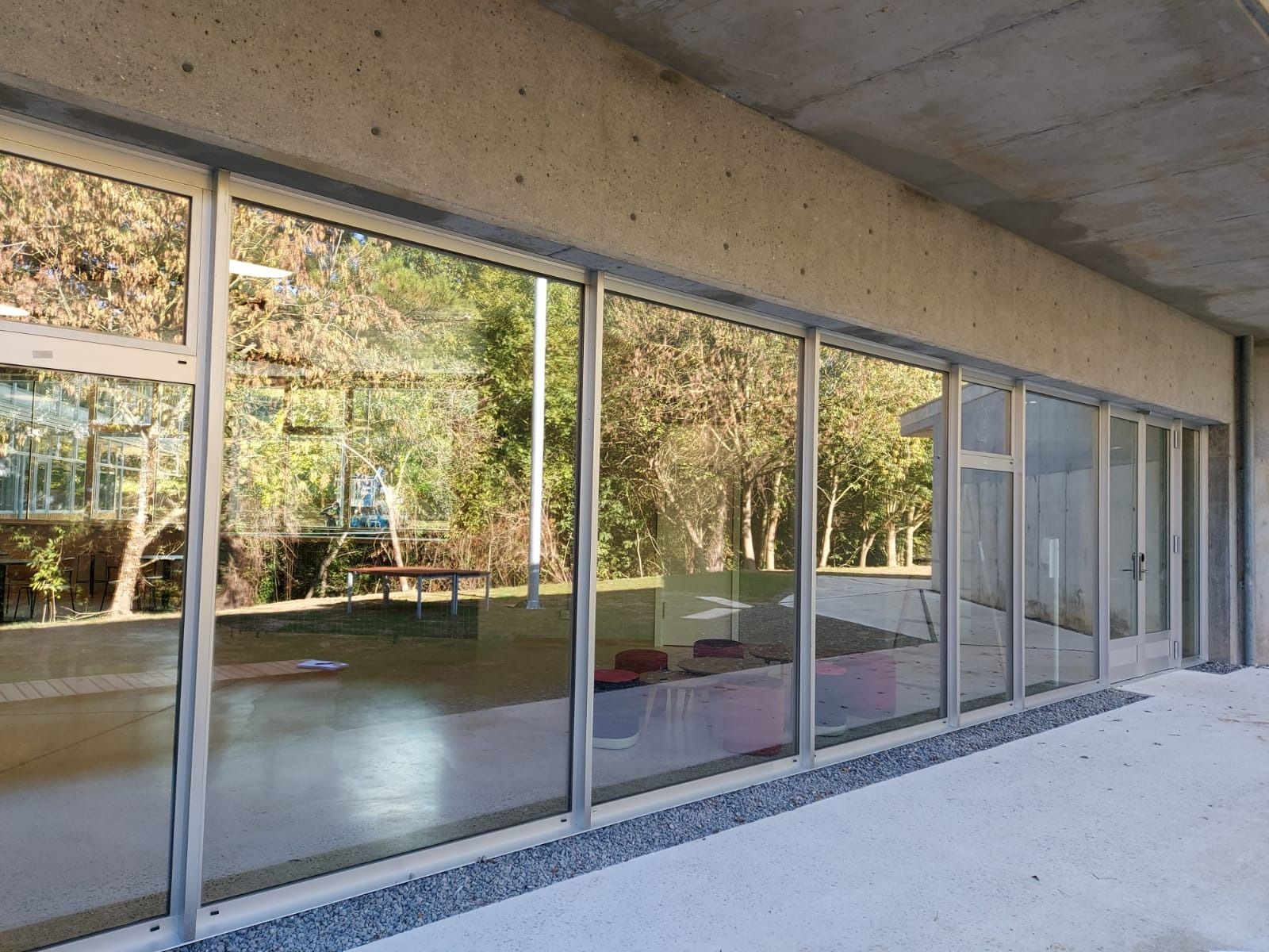 Un edificio con muchas ventanas y árboles reflejados en las ventanas.