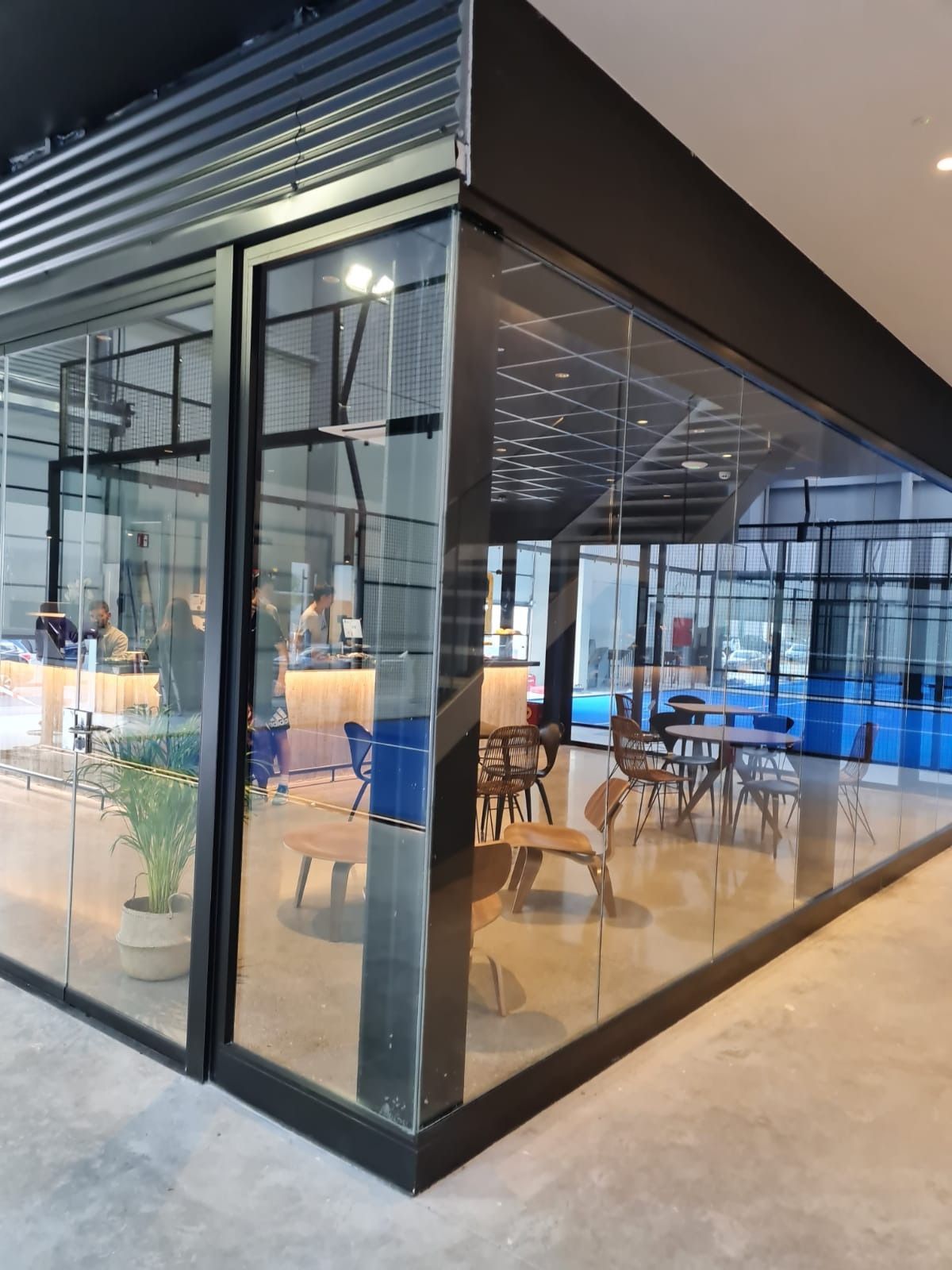 Una habitación con mesas y sillas dentro de un edificio con muchas ventanas.