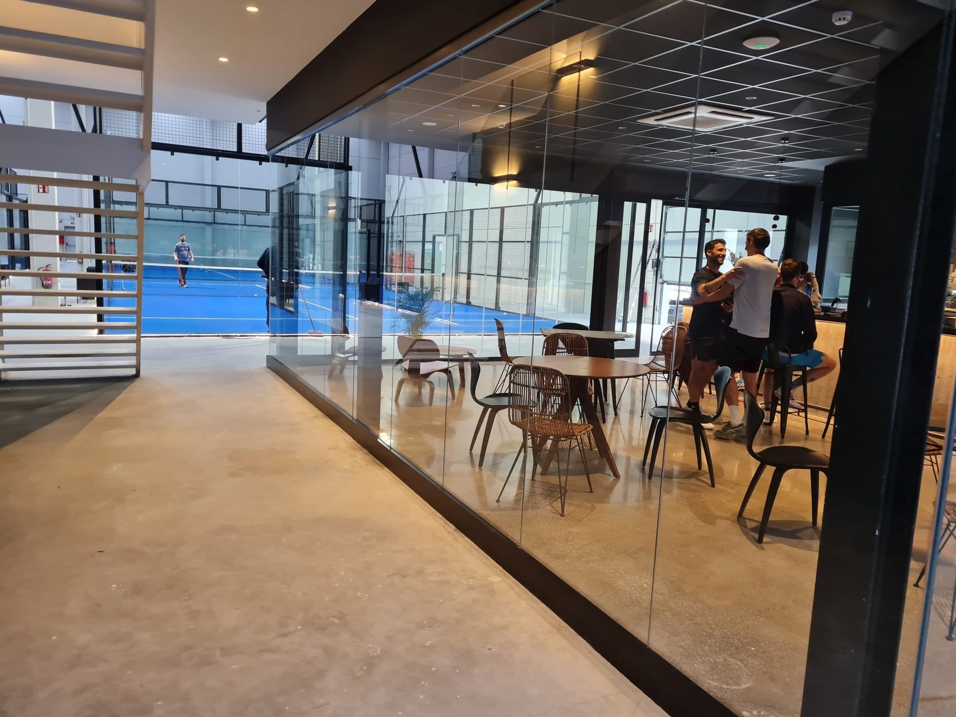 Un grupo de personas está de pie en una habitación con mesas y sillas.