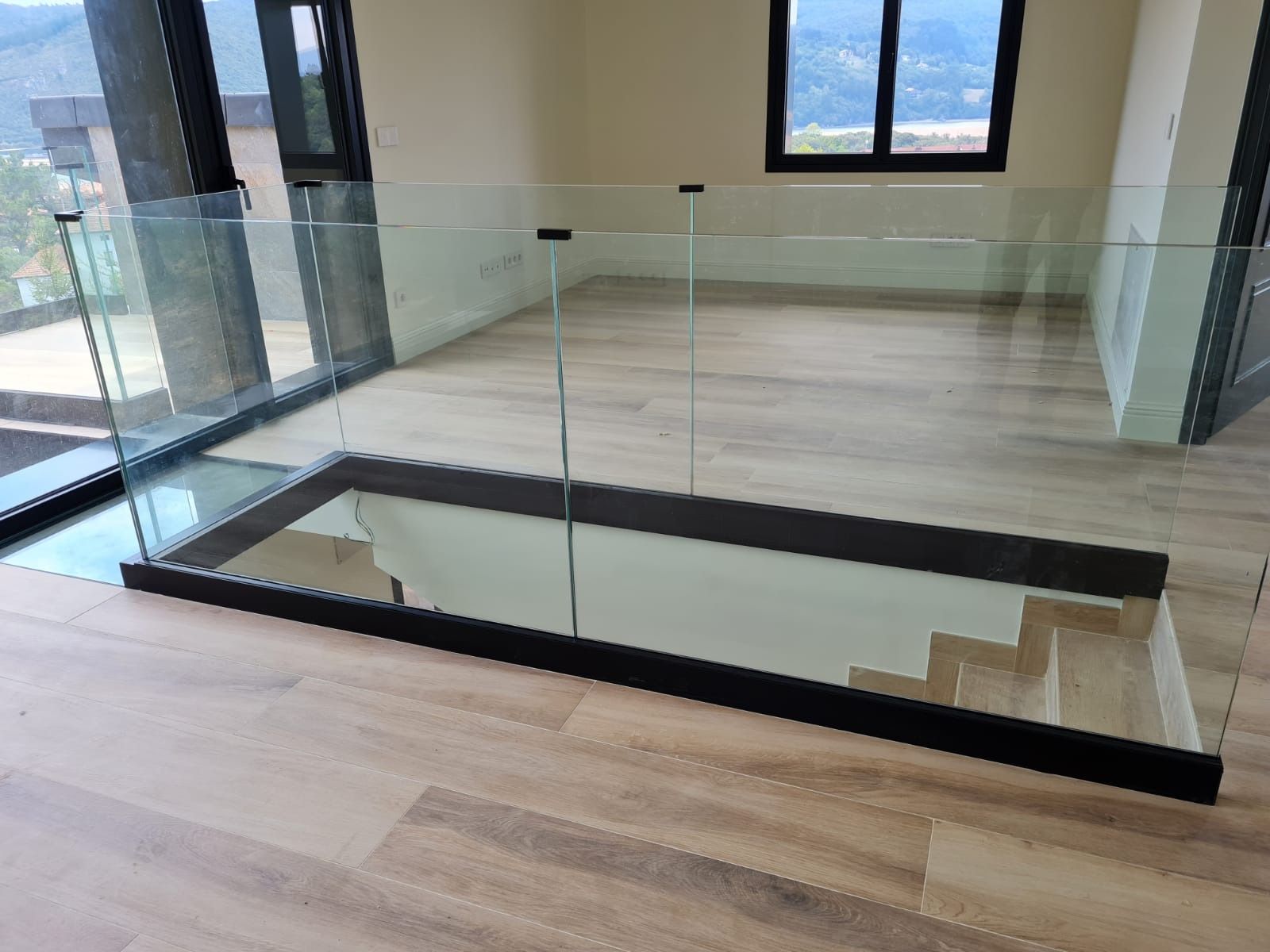 Una escalera con barandilla de cristal y suelo de madera.