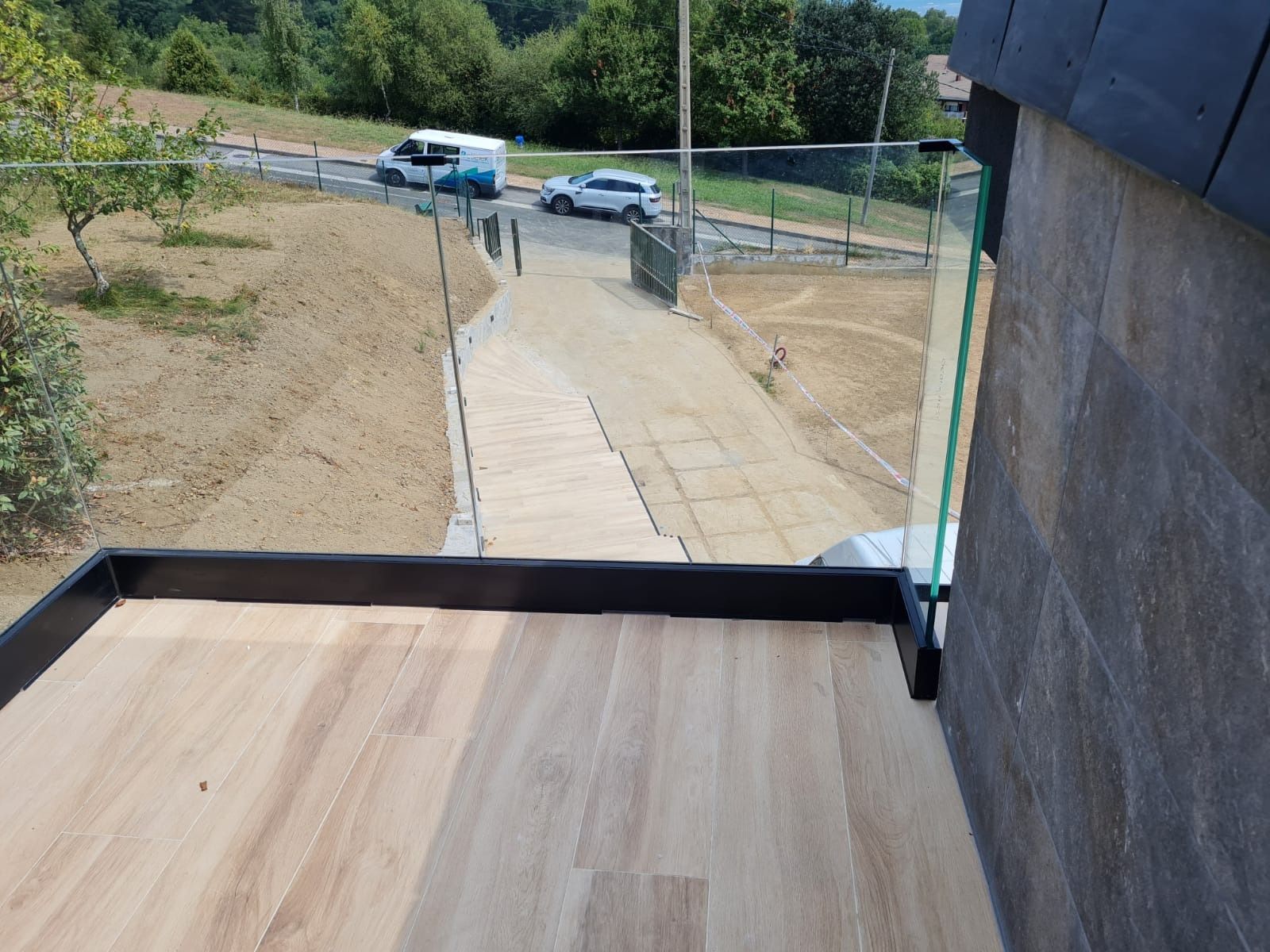 Un balcón con suelo de madera y barandilla de cristal.