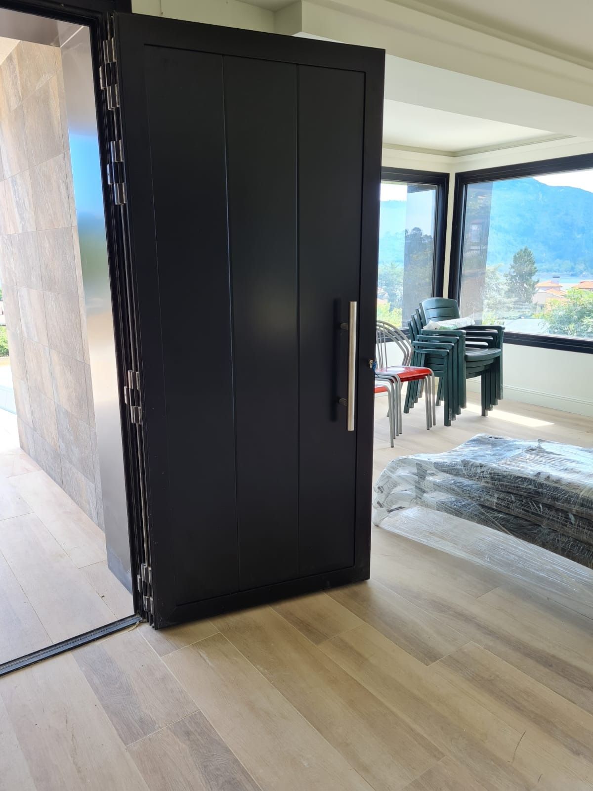 Una puerta negra se abre a una sala de estar con una mesa y sillas.