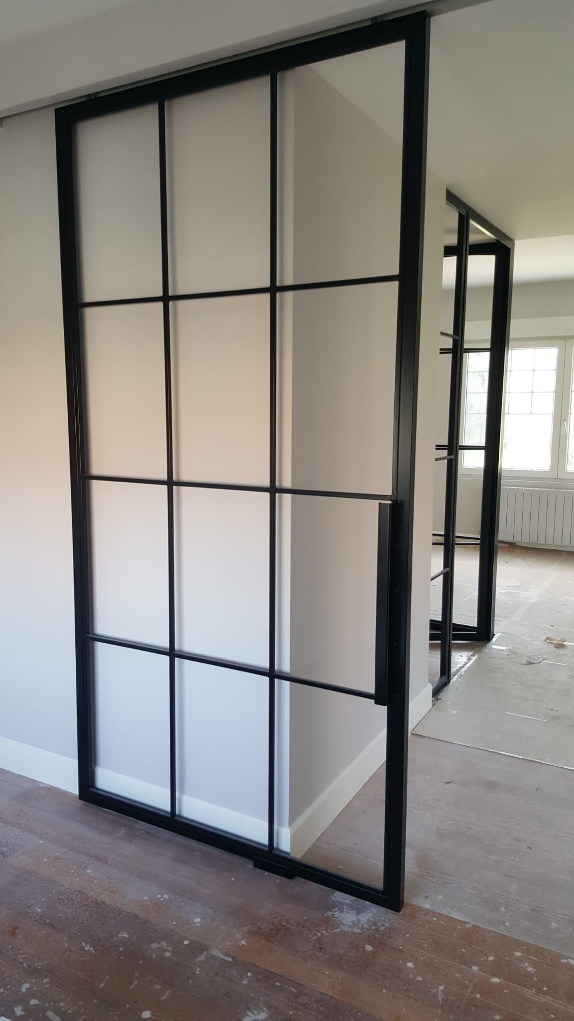 Una habitación con una puerta corrediza de vidrio entre dos habitaciones.