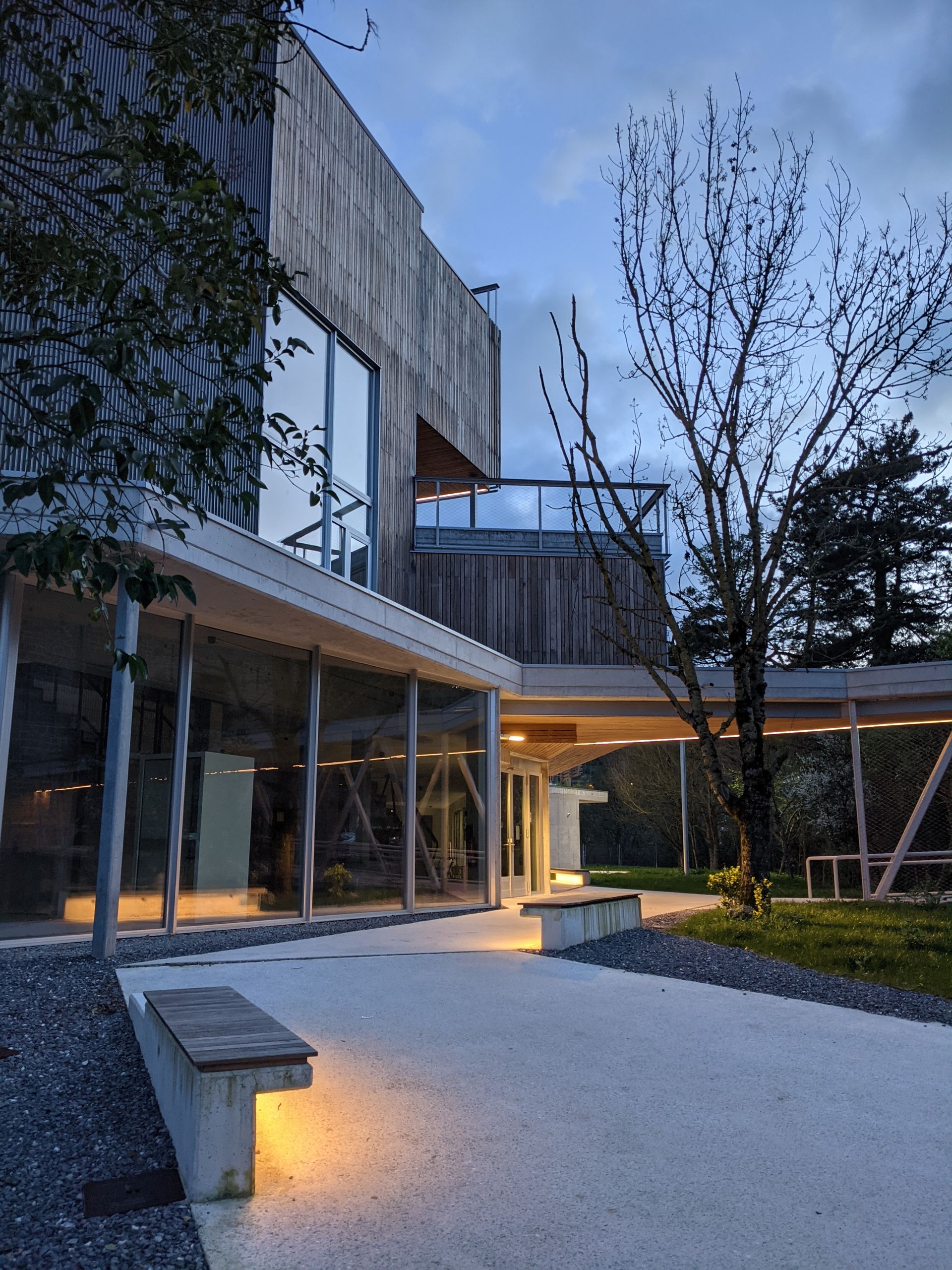Un edificio grande con muchas ventanas y un banco delante de él.