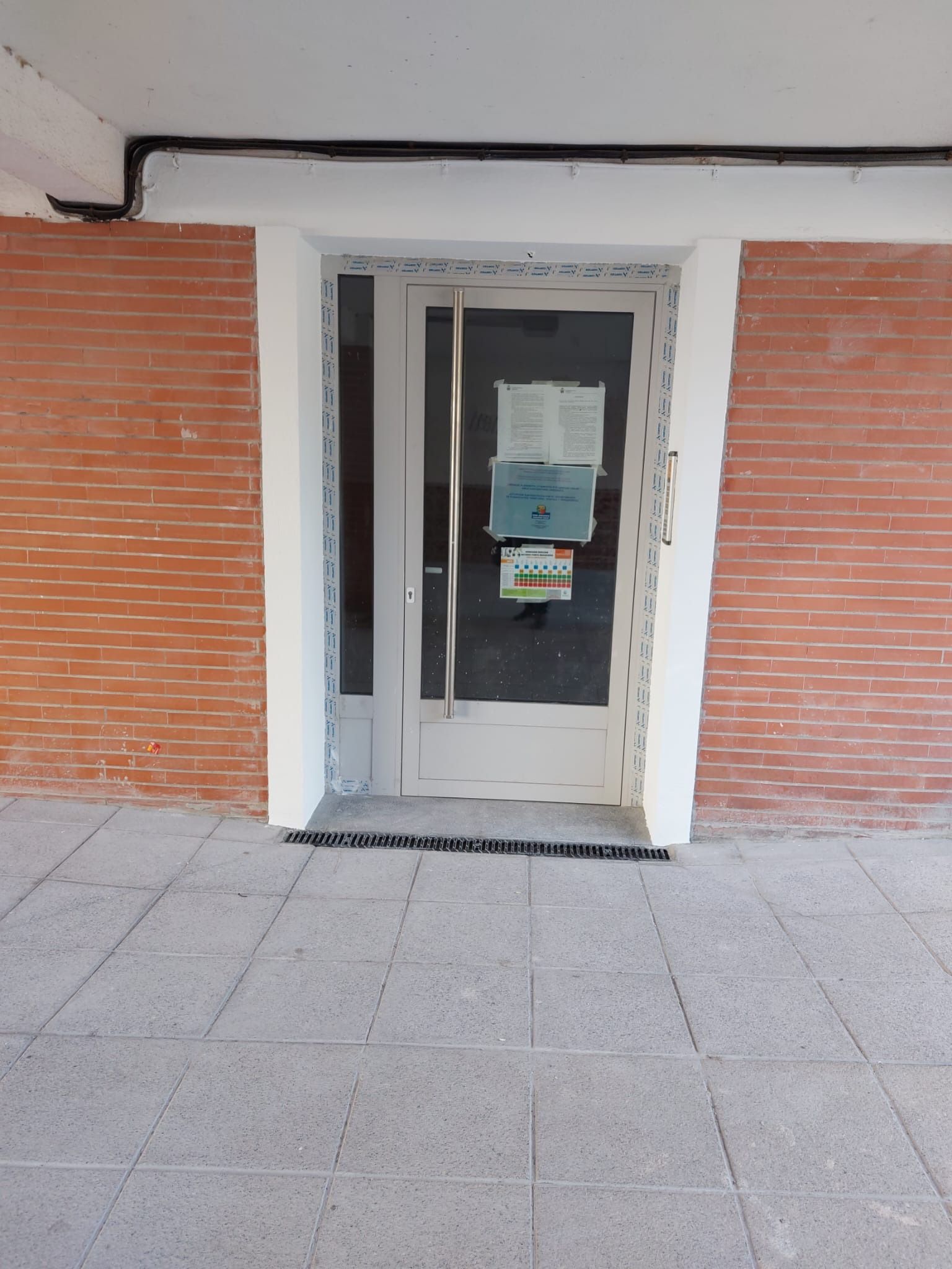 Un edificio de ladrillo con una puerta blanca y un cartel.