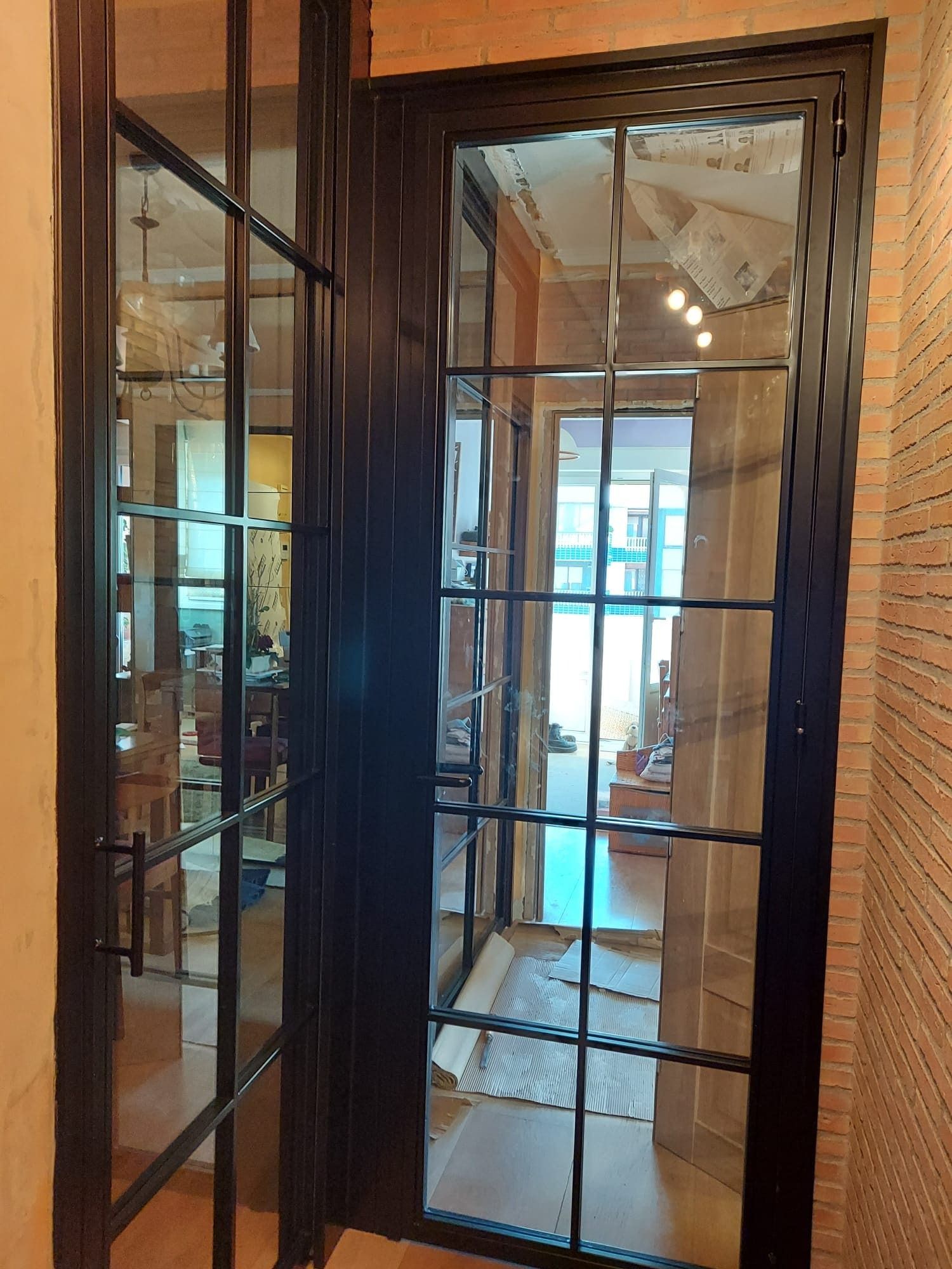 Una puerta con mucho vidrio en una habitación con una pared de ladrillos.