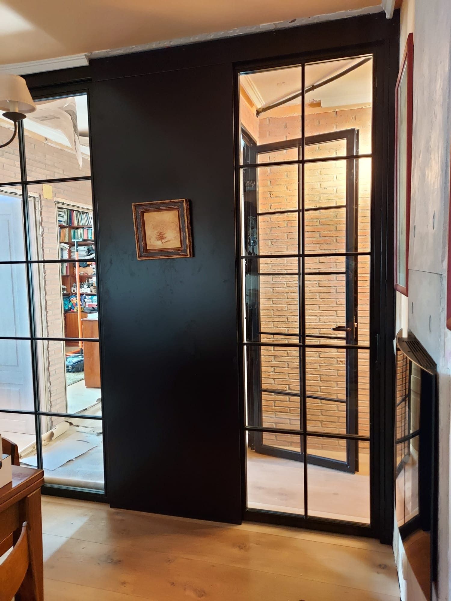 Una sala de estar con una pared negra y una puerta de vidrio que conduce a una pared de ladrillos.