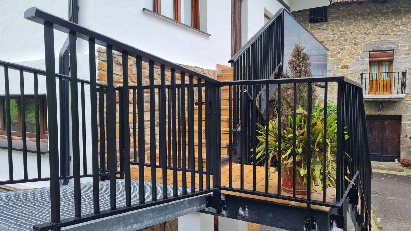 Una escalera de metal con barandilla negra que conduce a un balcón.