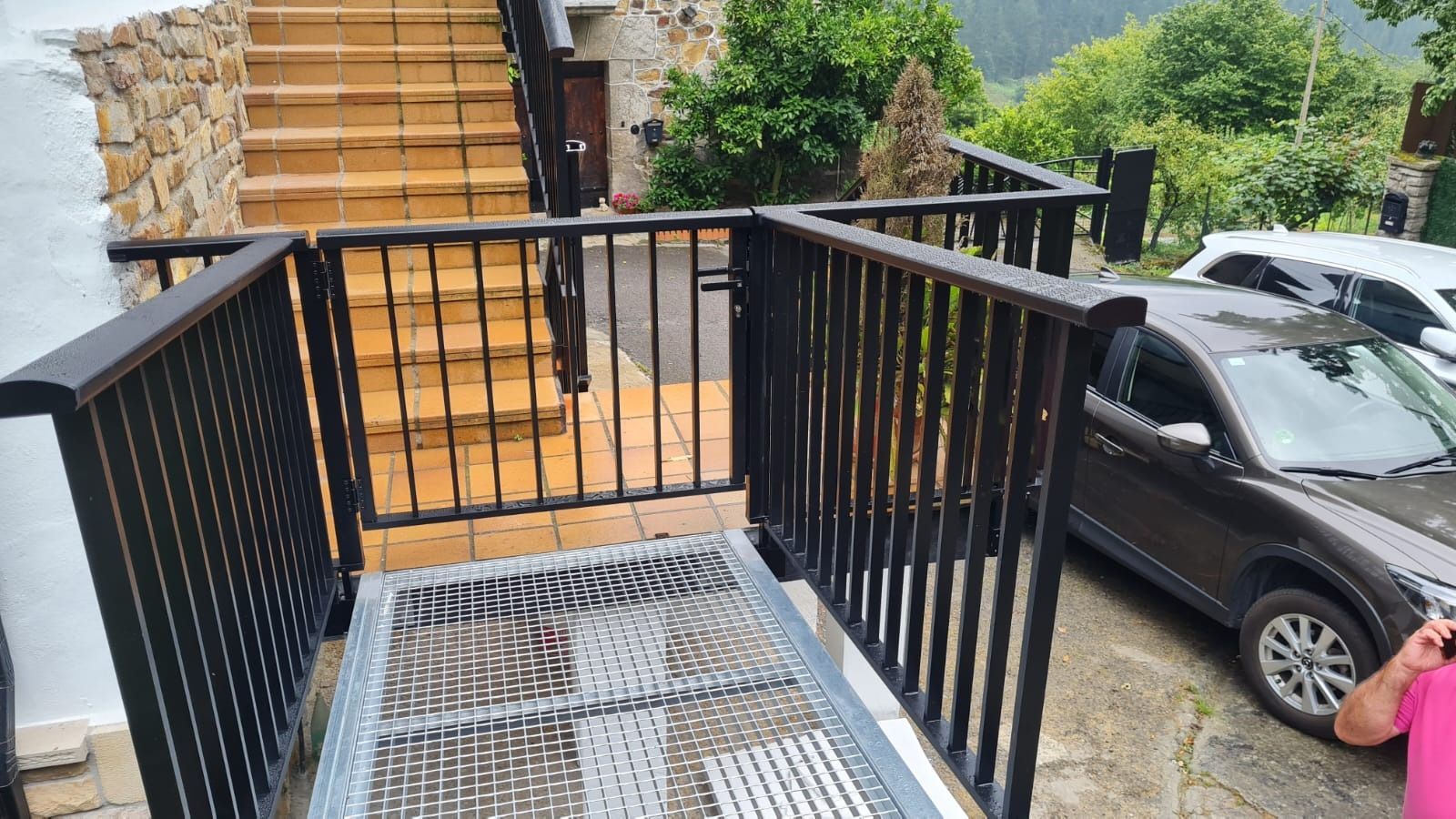 Un coche está aparcado al lado de la carretera al lado de un balcón.