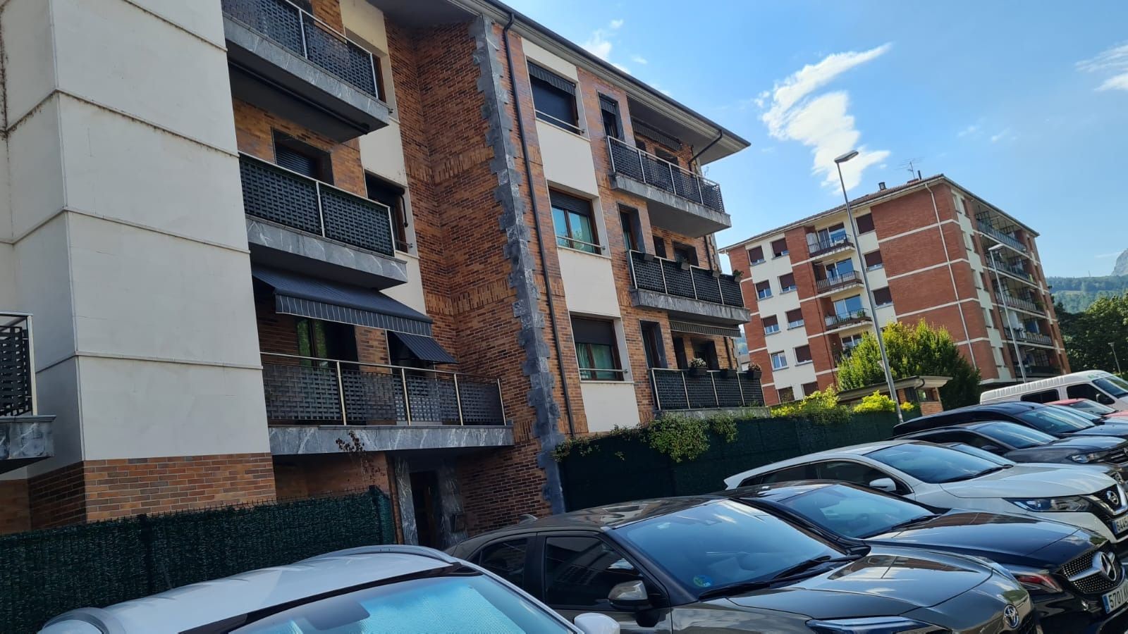 Una fila de coches están aparcados delante de un edificio.